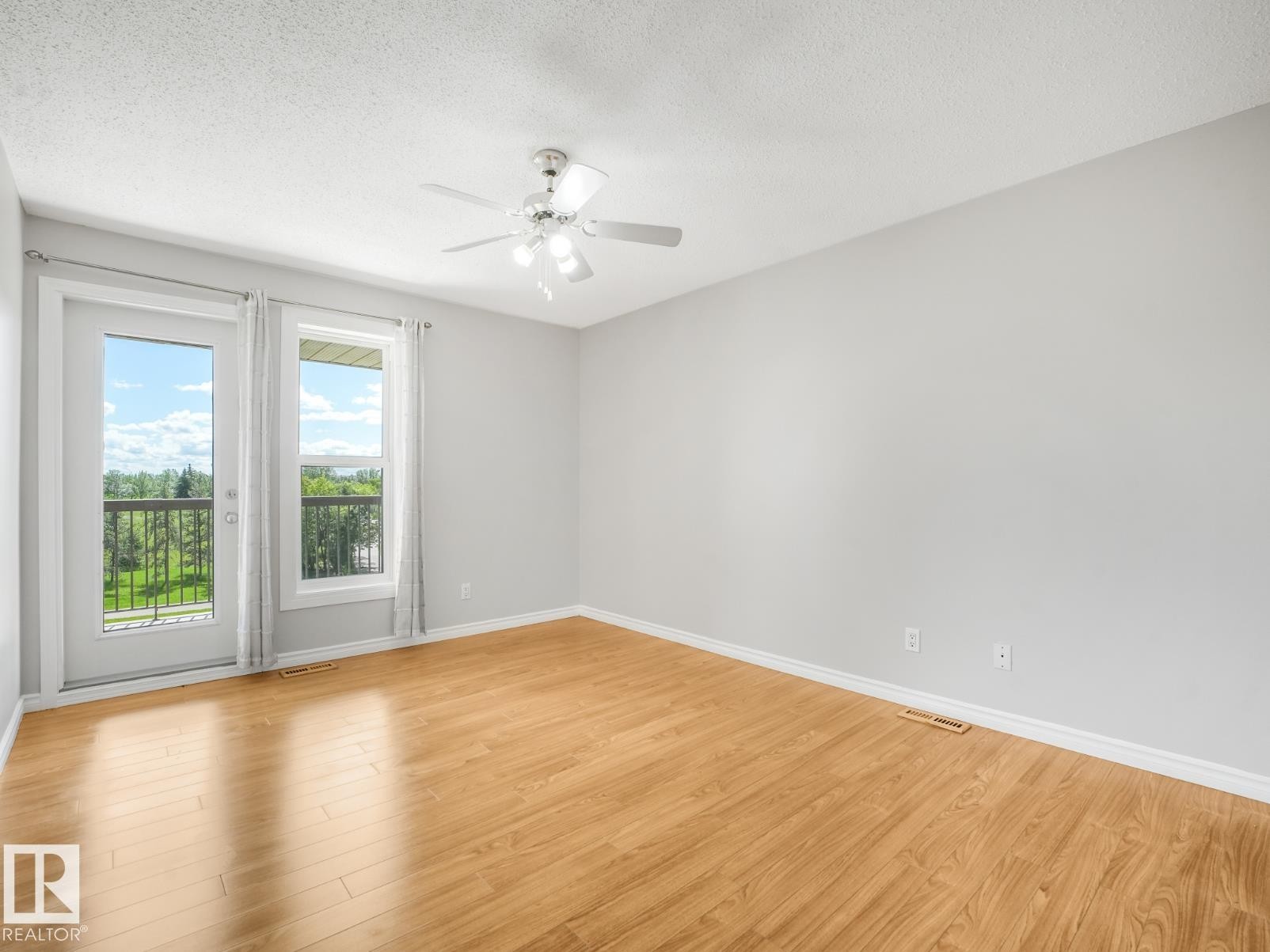 Bright room featuring wood-finish flooring, light grey walls, and a ceiling fan - #301 10528 29 Av Nw, Edmonton, AB