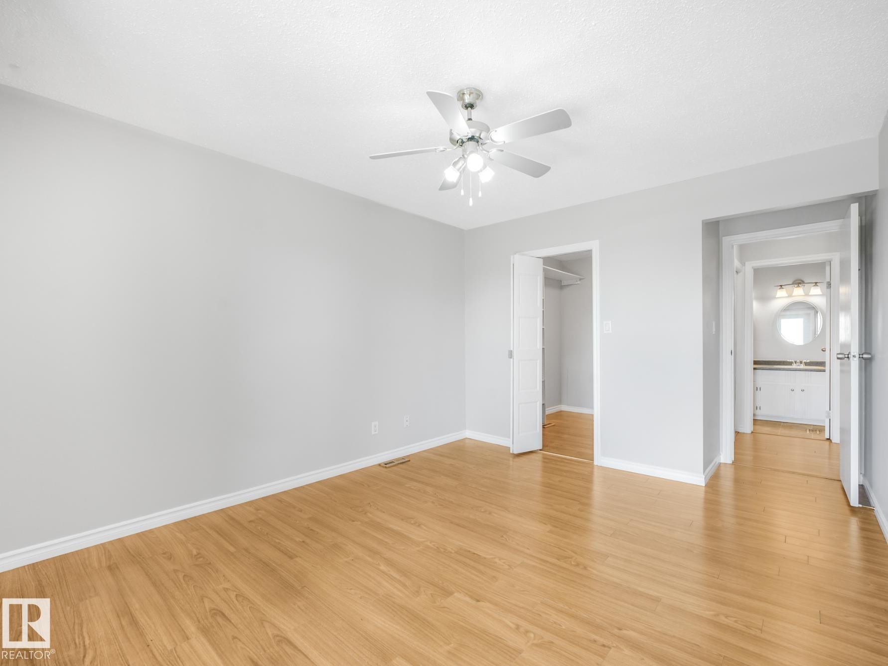 Spacious room featuring light wood-finish flooring, light gray wall paint, and white trim - #301 10528 29 Av Nw, Edmonton, AB