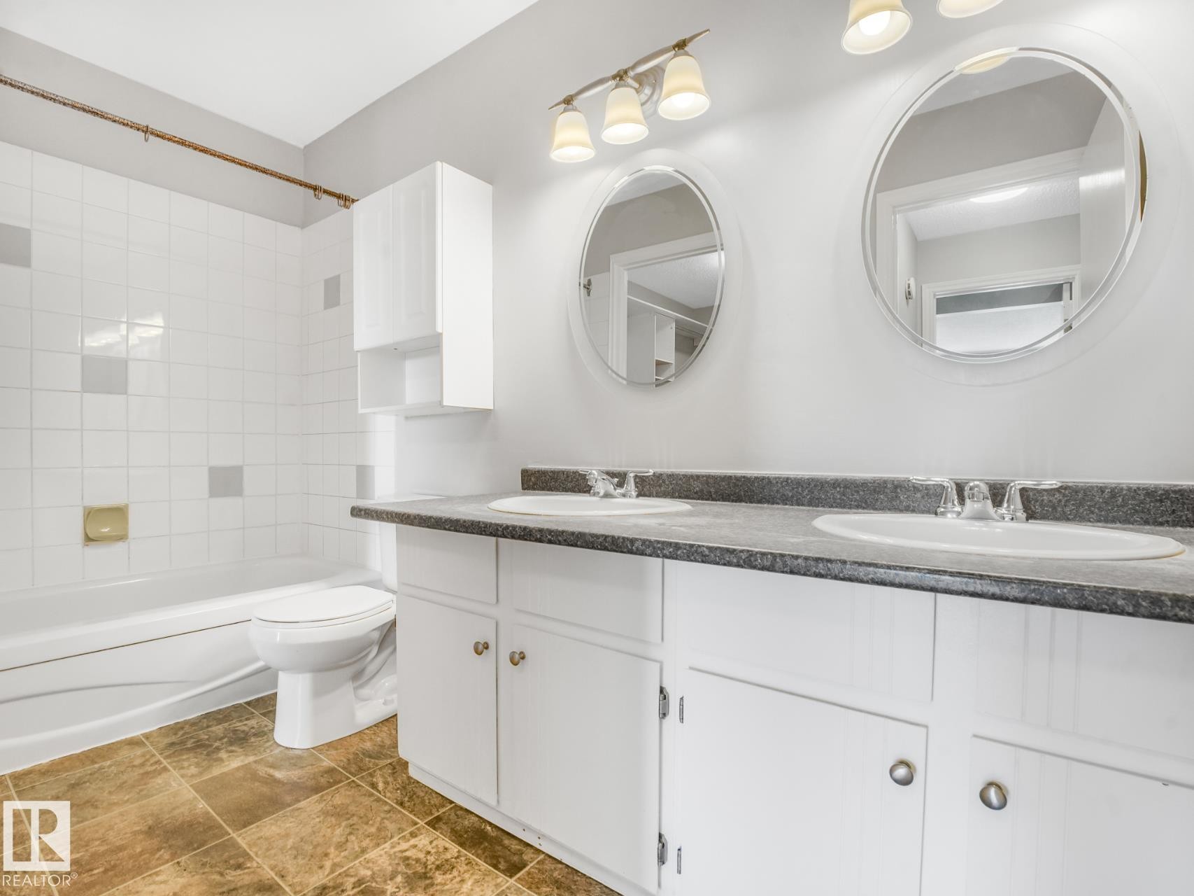 Bathroom featuring a dual-sink vanity with a dark countertop and white cabinetry - #301 10528 29 Av Nw, Edmonton, AB