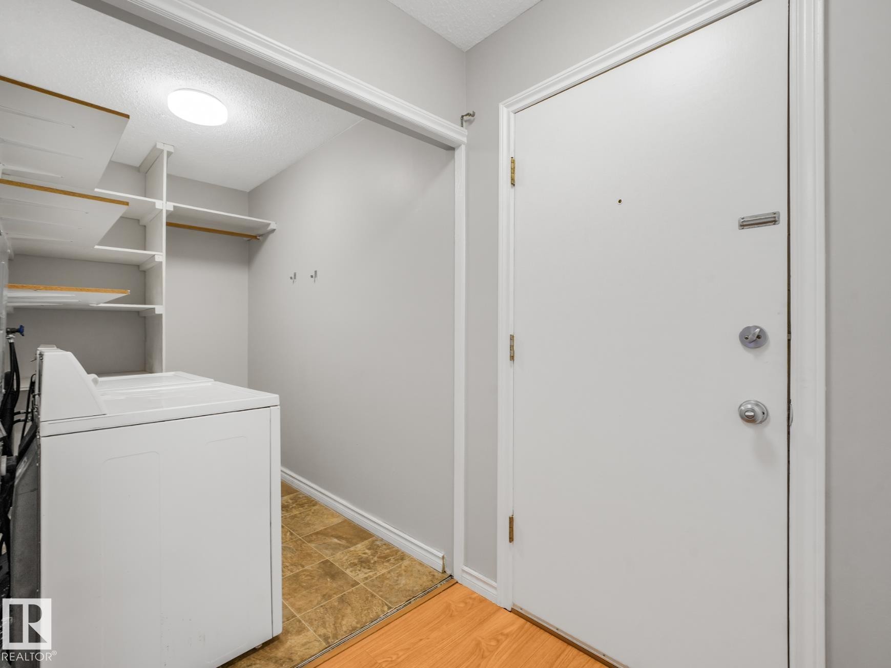 Entryway with a white door, chrome hardware, and wood-finish flooring - #301 10528 29 Av Nw, Edmonton, AB