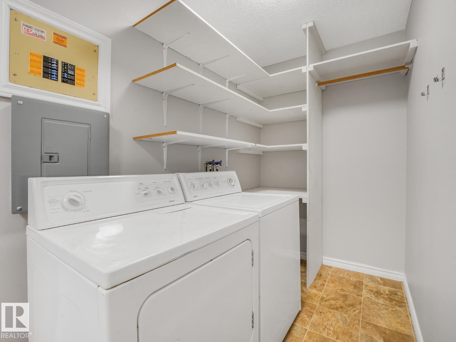 Dedicated laundry area featuring a washer and dryer, built-in shelving, a clothes hanging rod, and sheet vinyl flooring - #301 10528 29 Av Nw, Edmonton, AB