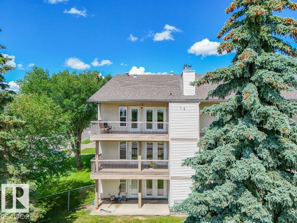 Multi-level dwelling featuring three balconies with white railings, a light-colored siding exterior, and a brown shingle roof - #301 10528 29 Av Nw, Edmonton, AB