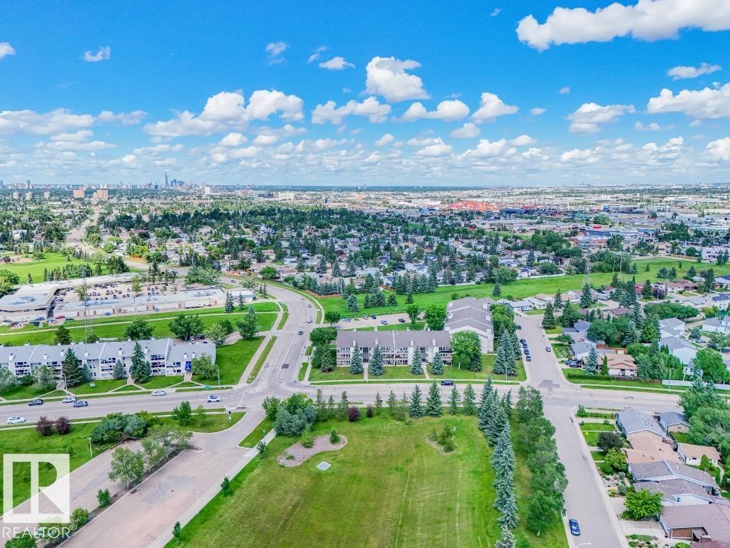Aerial perspective showcasing a residential area with varied housing types, extensive green spaces, and mature tree lines - #301 10528 29 Av Nw, Edmonton, AB