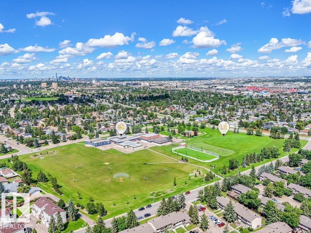 Aerial perspective showcasing extensive green spaces, including a large playing field and a sports court - #301 10528 29 Av Nw, Edmonton, AB