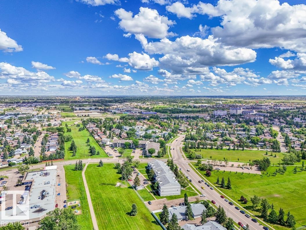 Aerial perspective showcasing a residential area with extensive green spaces and mature trees - #301 10528 29 Av Nw, Edmonton, AB
