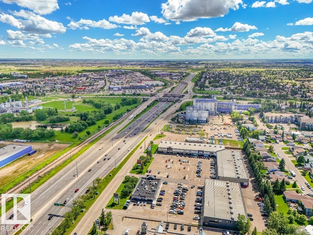 Aerial perspective showcasing a multi-lane highway, surrounding commercial structures, and residential areas - #301 10528 29 Av Nw, Edmonton, AB