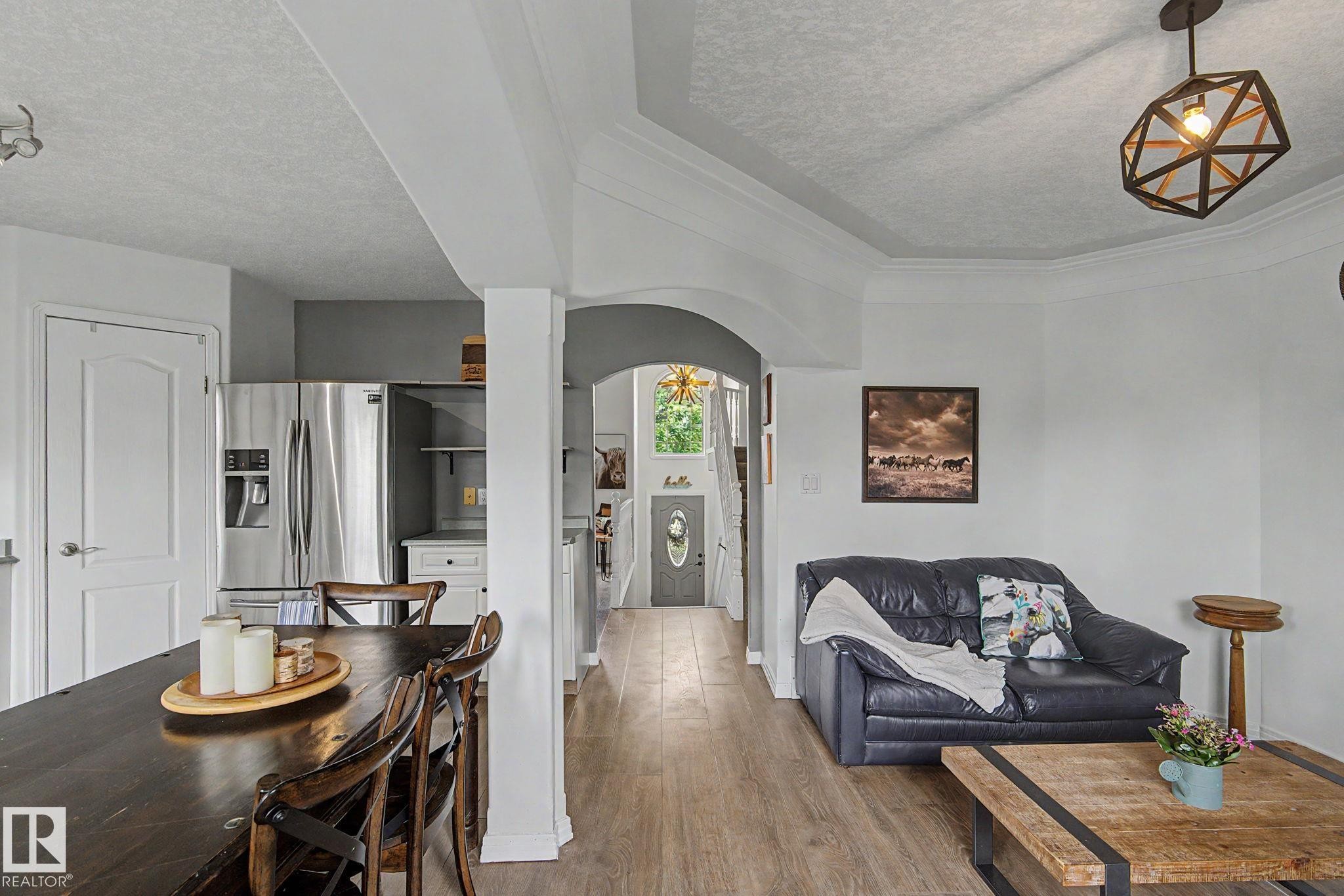 Open-concept living area featuring wood-finish flooring, crown molding, an arched entryway, and recessed lighting - 1619 Welbourn Cove, Edmonton, AB