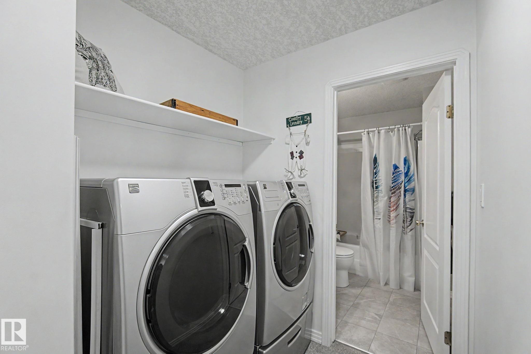 Laundry area featuring a side-by-side washer and dryer, an overhead shelf, and a white interior door - 1619 Welbourn Cove, Edmonton, AB