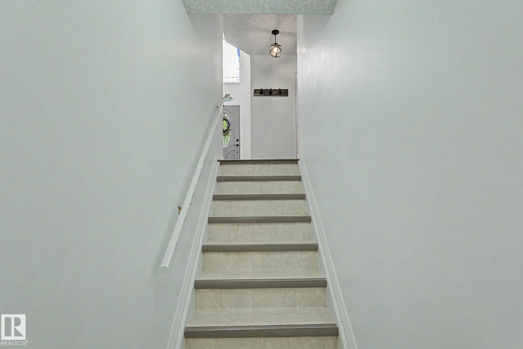 Staircase featuring light-toned treads, white risers, and a white handrail - 1619 Welbourn Cove, Edmonton, AB