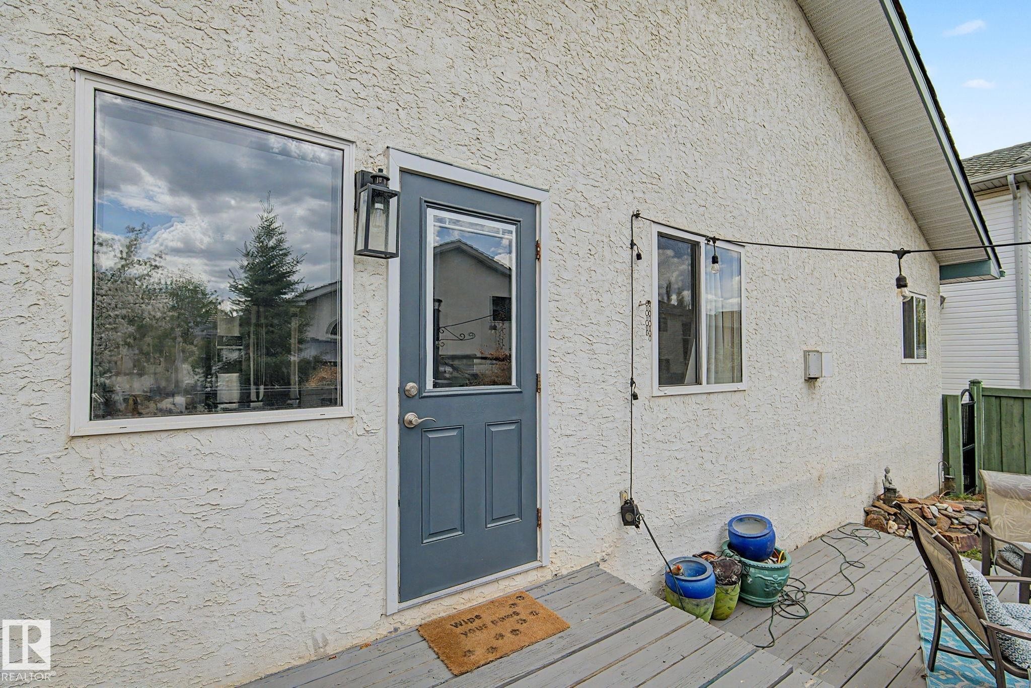 Exterior wall with stucco finish and a contrasting gray door with an upper window pane - 1619 Welbourn Cove, Edmonton, AB