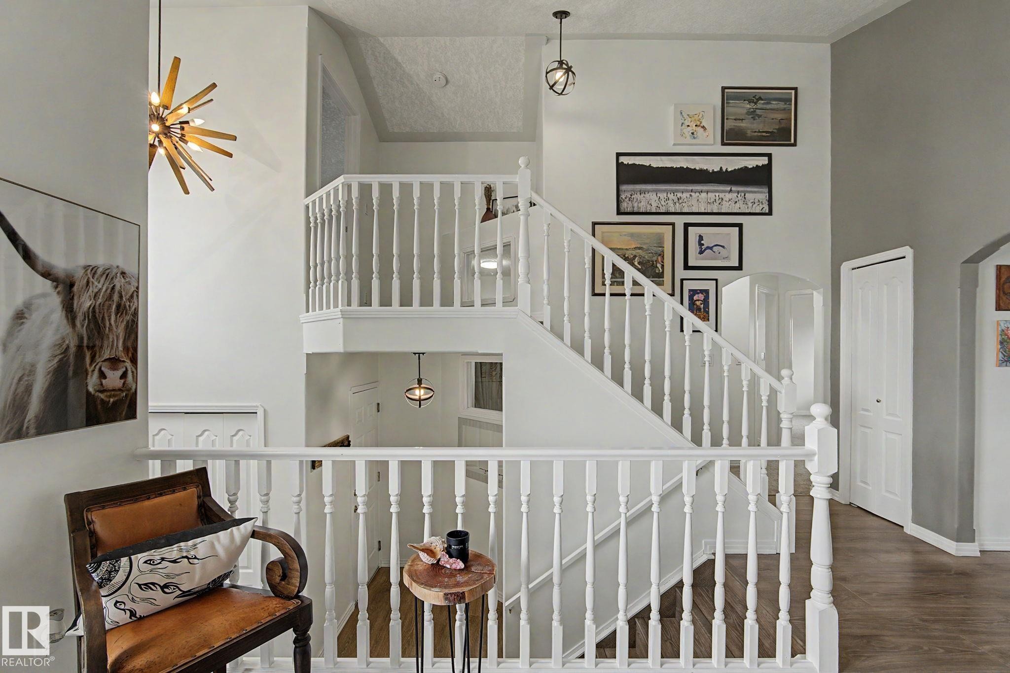 Two-story interior featuring a white spindle staircase and upper-level railing - 1619 Welbourn Cove, Edmonton, AB