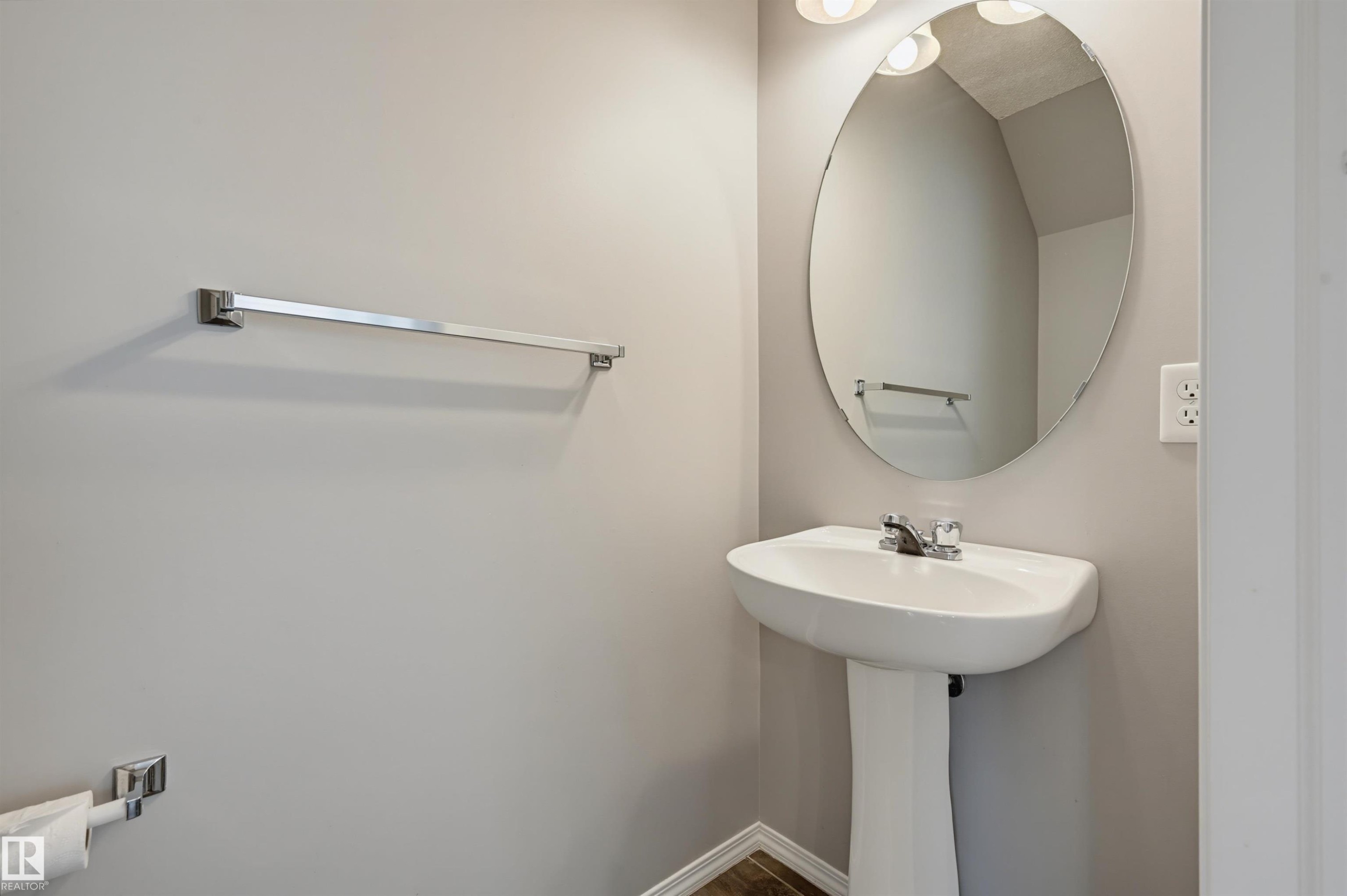 Pedestal sink with chrome faucet, complemented by an oval mirror and overhead vanity lighting - 126 2051 Towne Centre Boulevard, Edmonton, AB