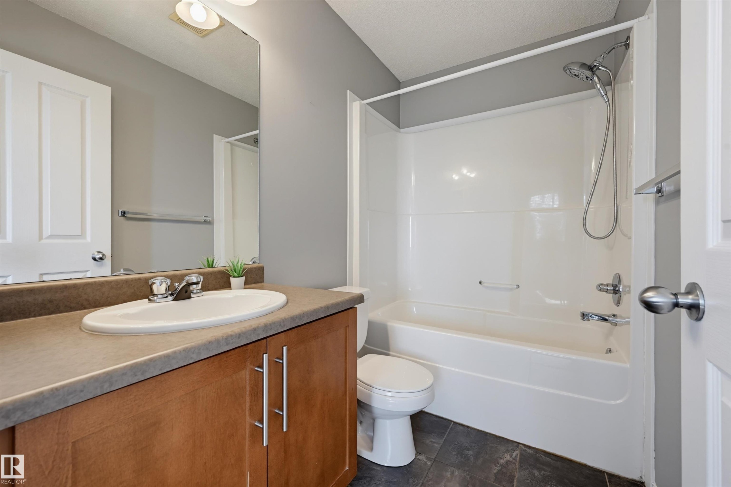 Bathroom featuring a wood-finish vanity with an integrated sink and a neutral-toned countertop - 126 2051 Towne Centre Boulevard, Edmonton, AB
