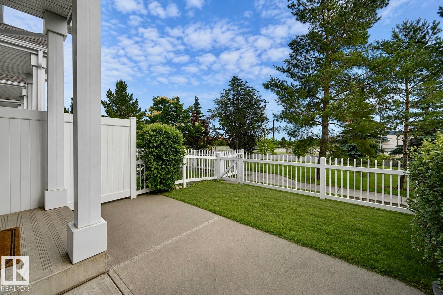 Private patio area featuring a concrete surface, white picket fence with gate, and manicured lawn - 126 2051 Towne Centre Boulevard, Edmonton, AB
