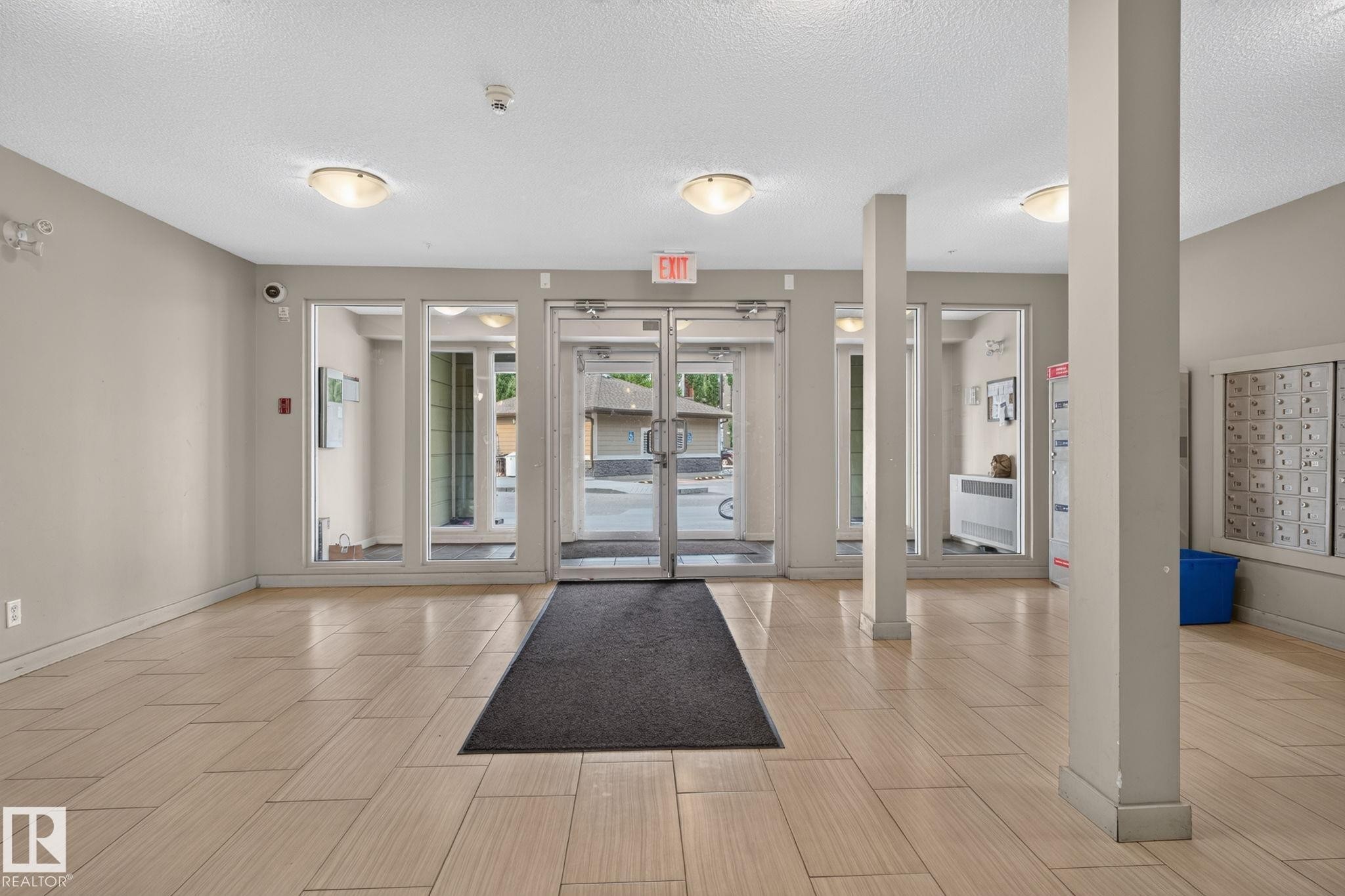 Spacious entry foyer featuring light-toned tile flooring, neutral wall paint, overhead flush-mount lighting, and floor-to-ceiling glass paneling at the entrance - 415 111 Watt Common, Edmonton, AB