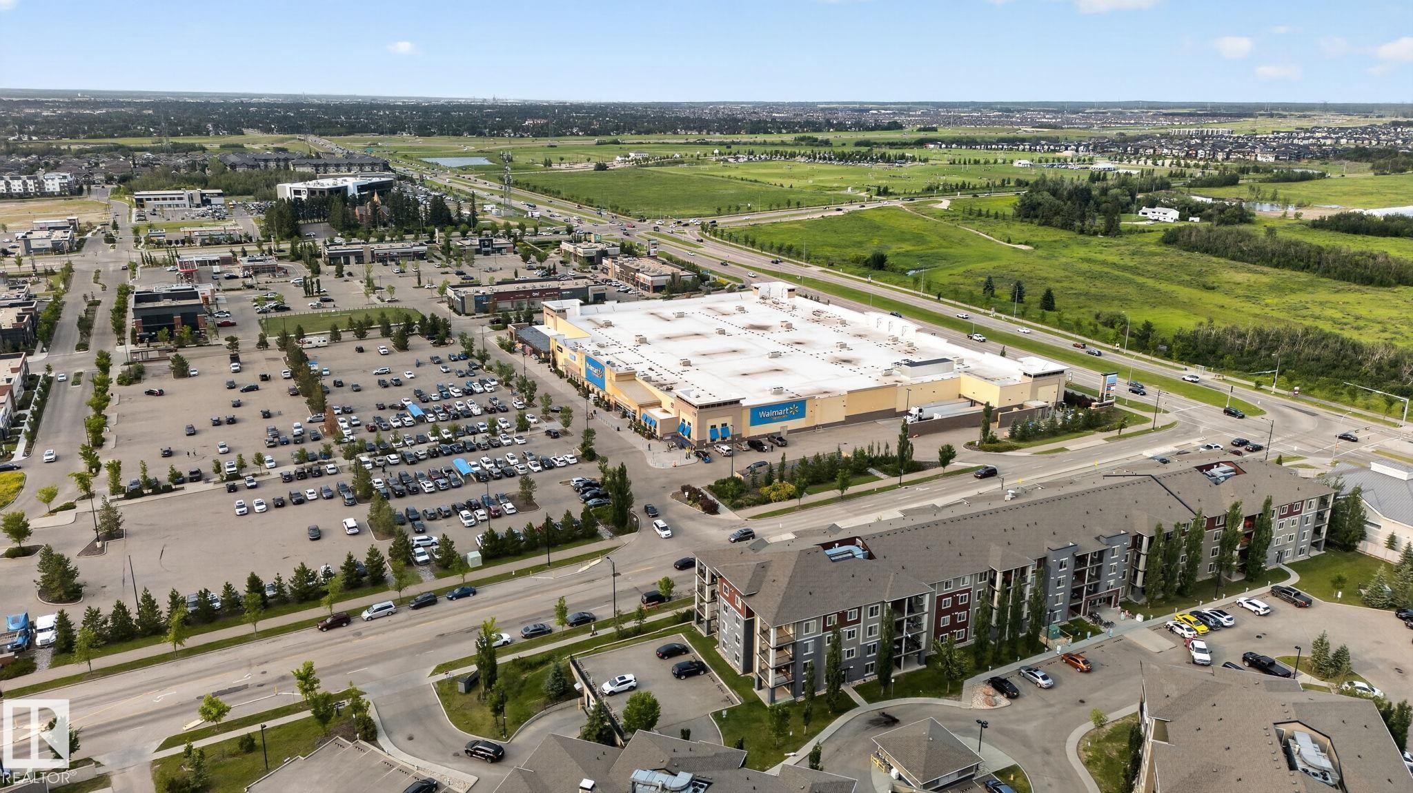 Aerial perspective showcasing a multi-story residential building with private balconies and surface parking - 415 111 Watt Common, Edmonton, AB
