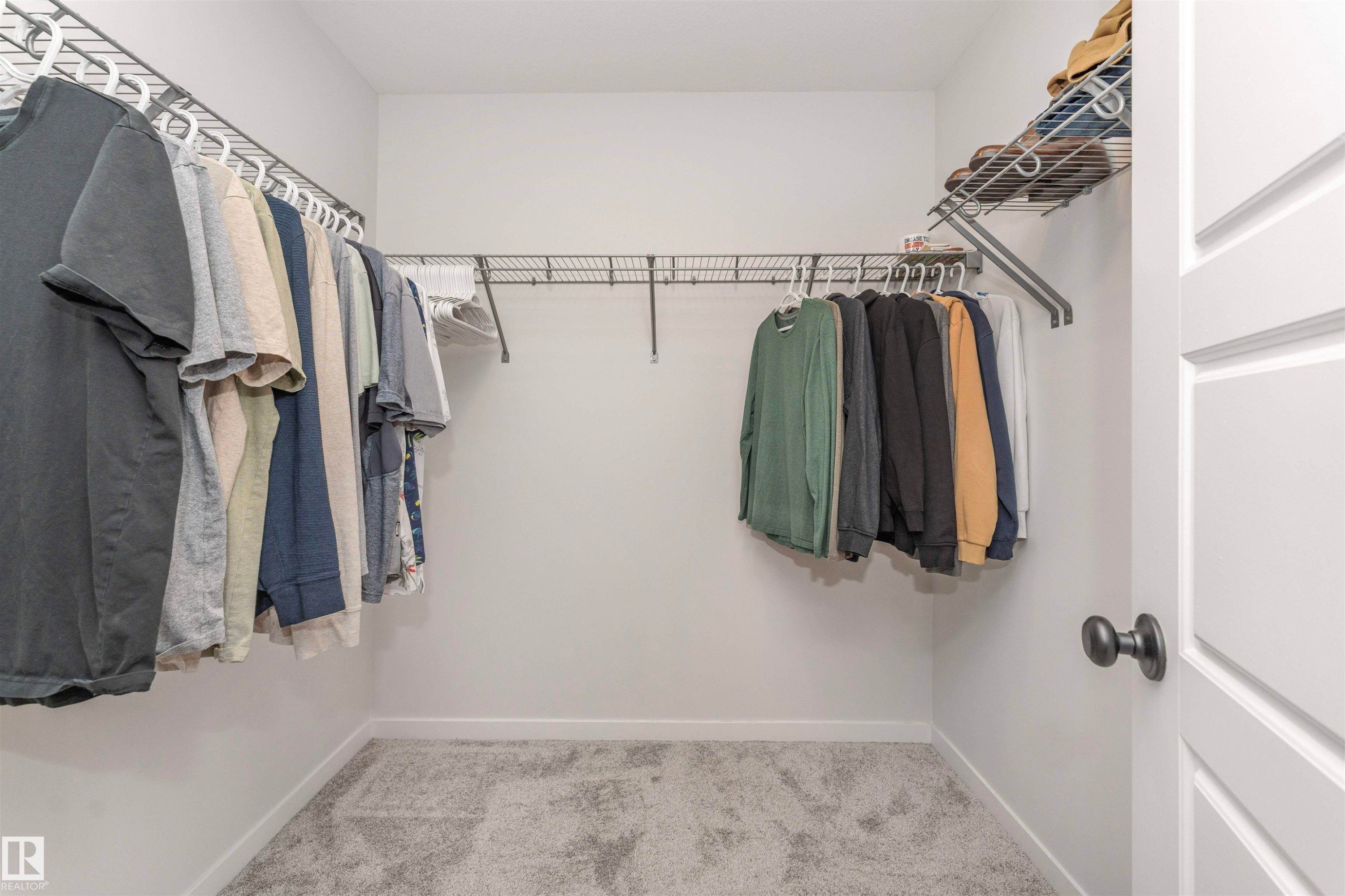 Walk-in closet featuring light gray carpeting, white walls, and wire shelving with hanging rods - 102 Horton Way, Ardrossan, AB