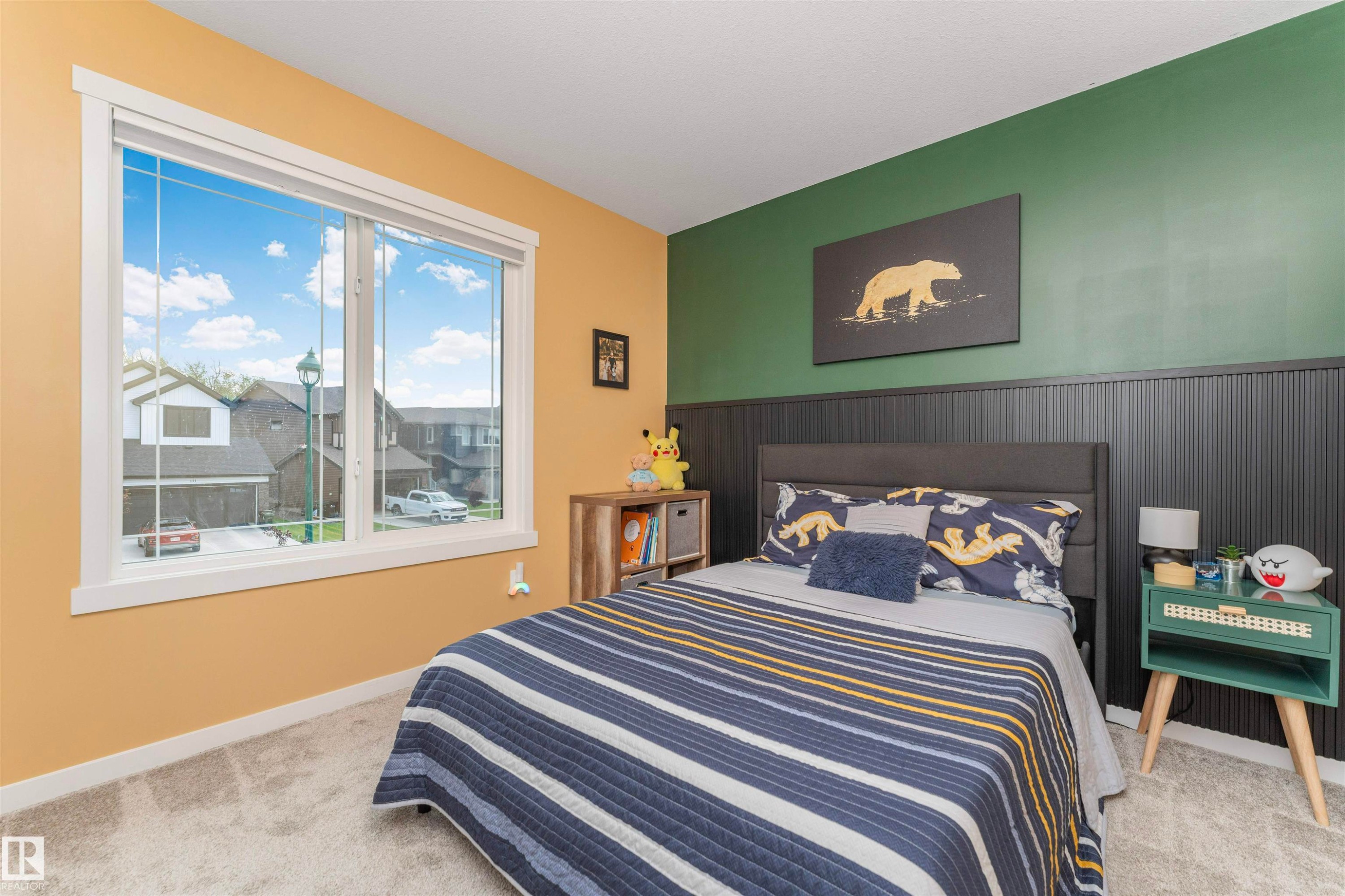 Bedroom featuring a large multi-pane window, plush carpet, and a paneled accent wall - 102 Horton Way, Ardrossan, AB