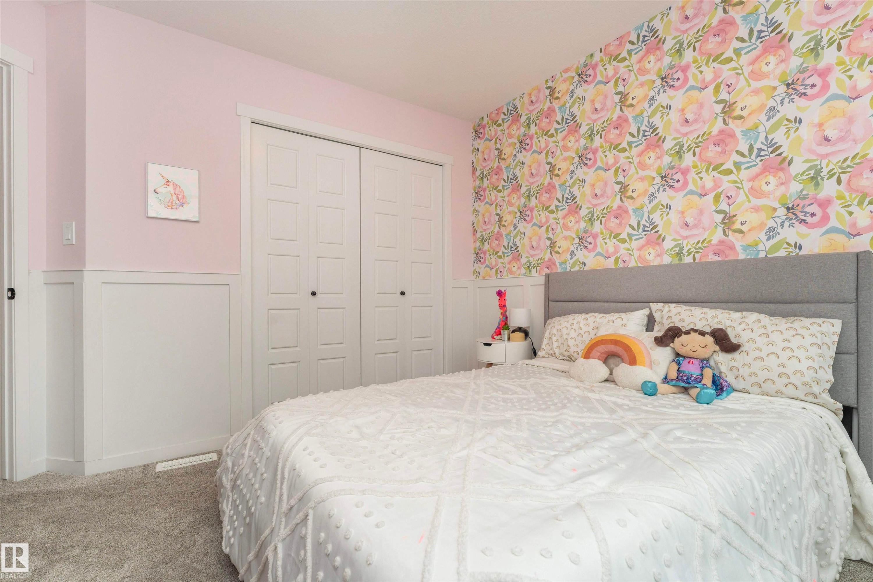 Bedroom featuring a floral accent wall, wainscoting, and carpet flooring - 102 Horton Way, Ardrossan, AB
