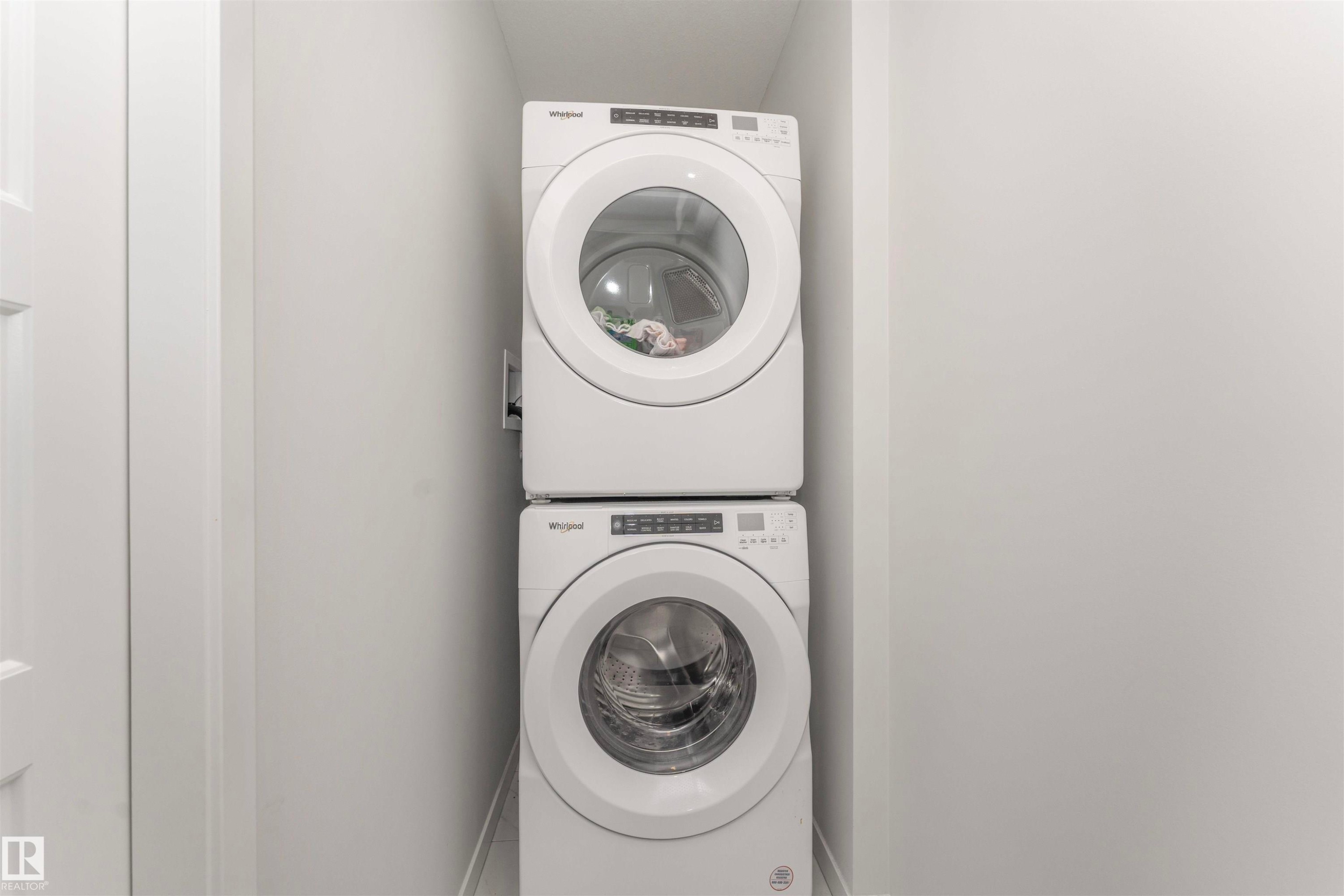 Dedicated laundry closet with stacked, front-loading washer and dryer units - 102 Horton Way, Ardrossan, AB