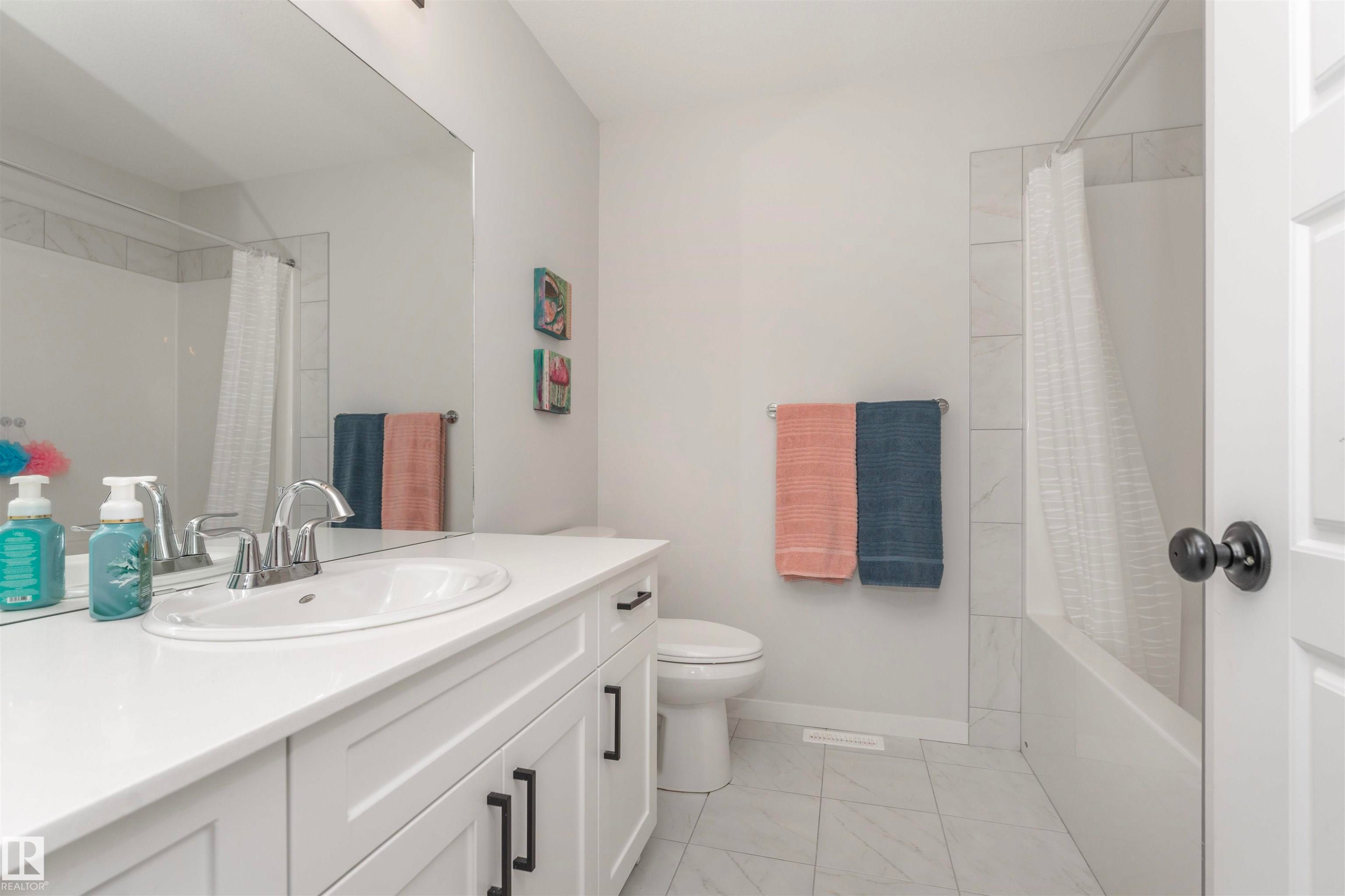 Bathroom featuring a white vanity with recessed panel cabinetry, white countertop, and an undermount sink - 102 Horton Way, Ardrossan, AB