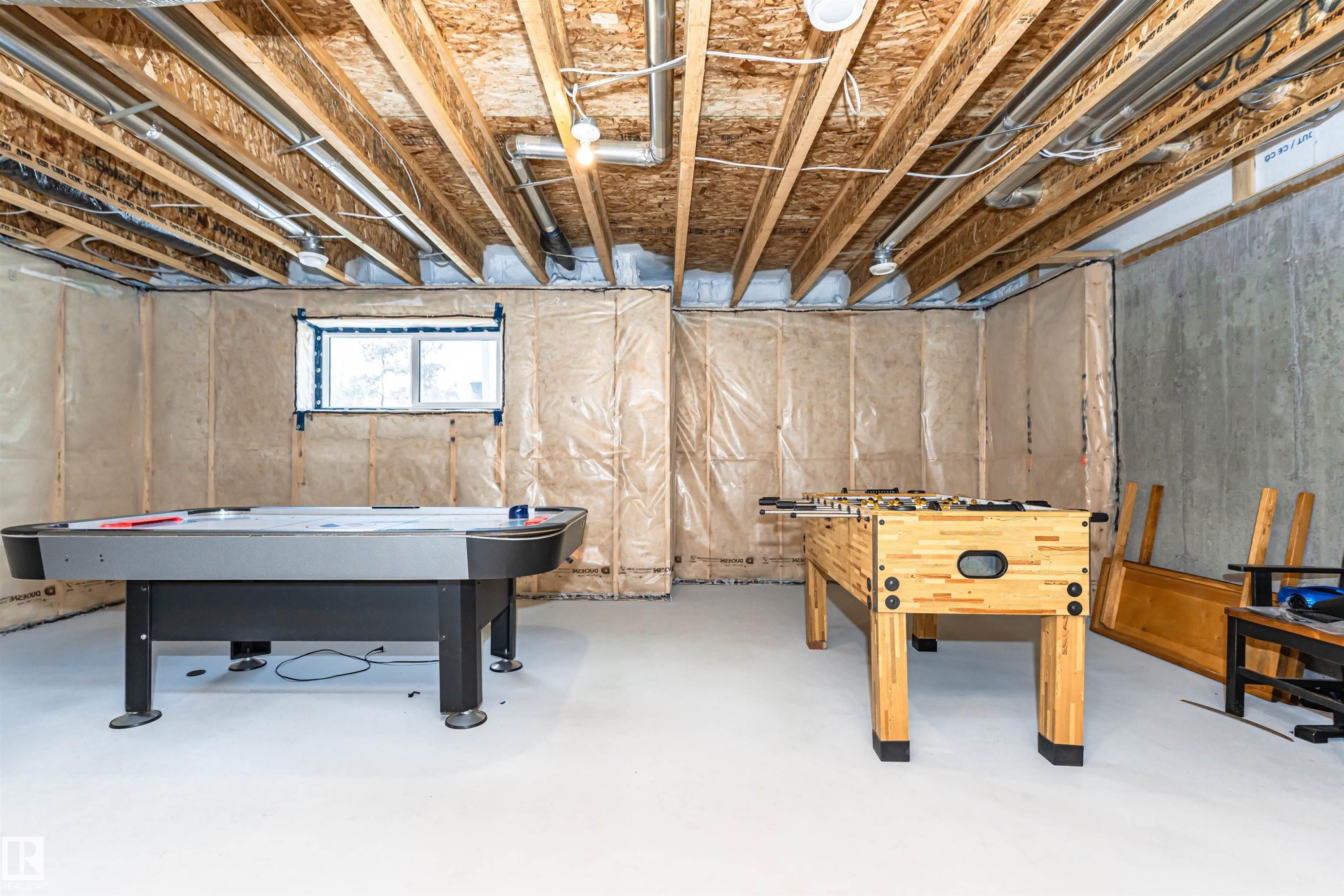 Unfinished basement featuring exposed wood joists, concrete walls, and a window - 102 Horton Way, Ardrossan, AB