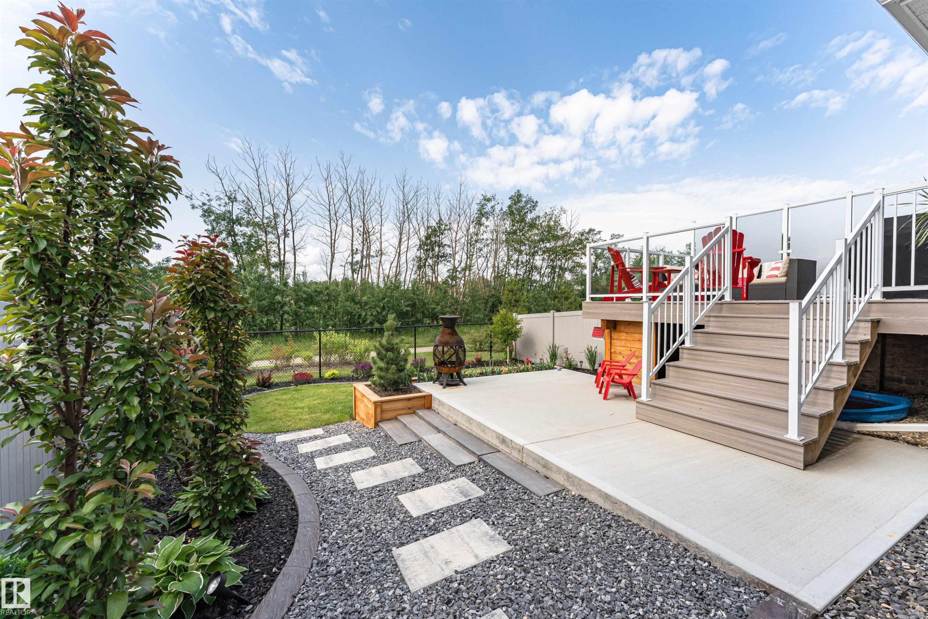 Multi-level outdoor living space featuring a composite deck with glass panel railings and a concrete patio - 102 Horton Way, Ardrossan, AB