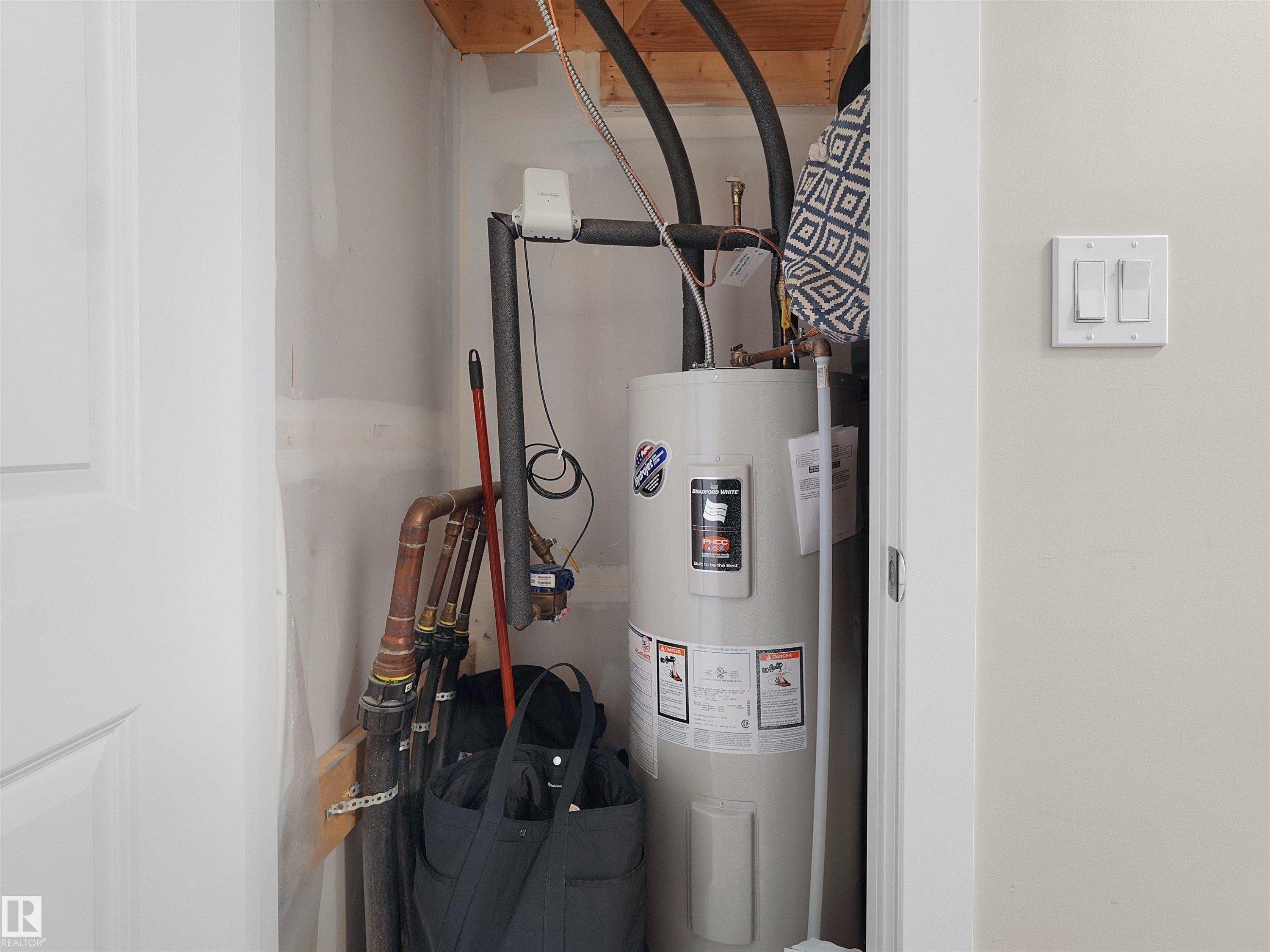 Water heater unit within a utility closet featuring exposed copper piping - #49 17832 78 St Nw, Edmonton, AB - Indoor Photo Showing Basement