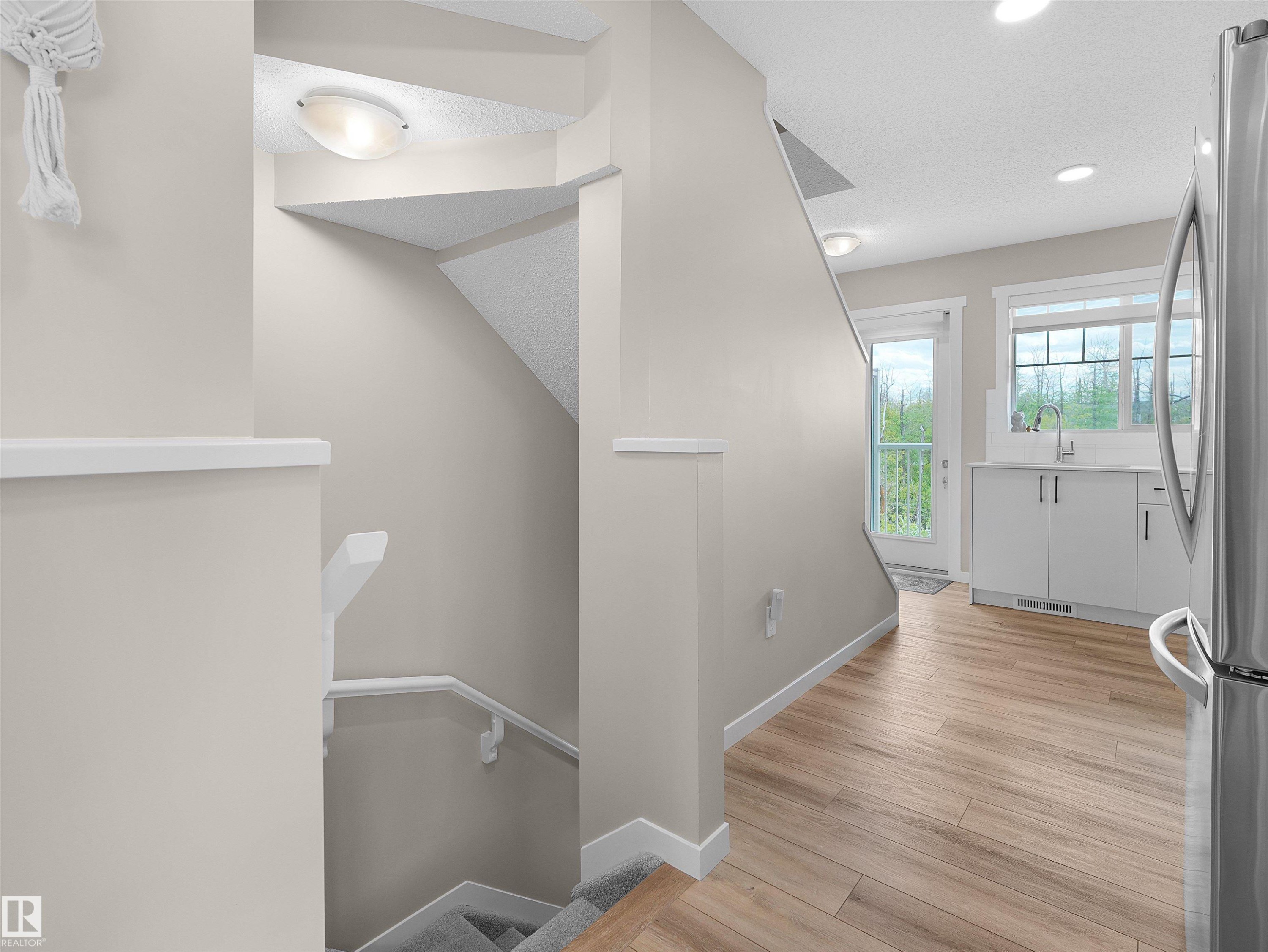 Staircase with white railing and carpeted treads, complemented by wood-finish flooring - #49 17832 78 St Nw, Edmonton, AB - Indoor Photo Showing Other Room