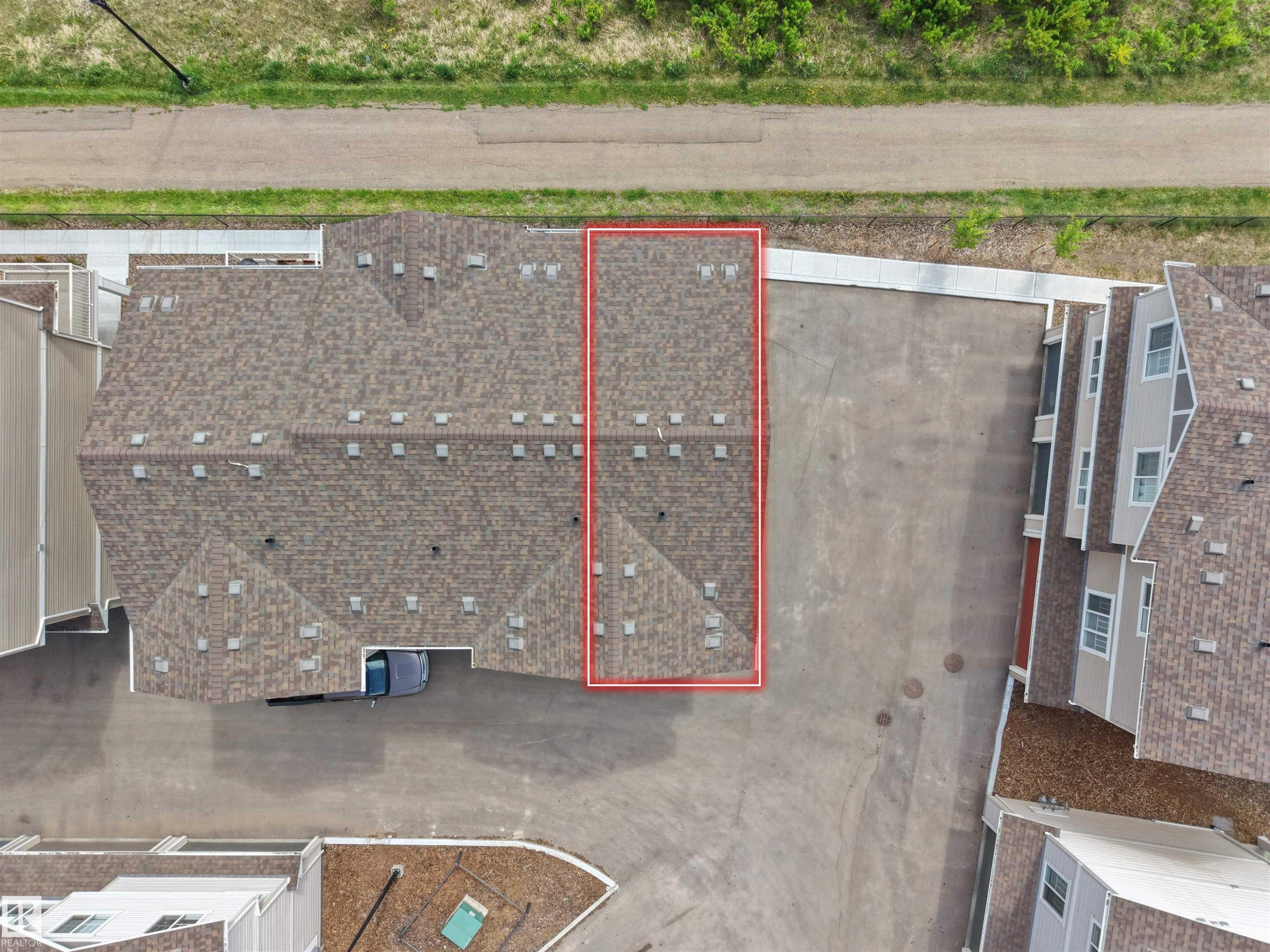 Townhome property with a multi-gabled roofline and light brown shingles, featuring a private driveway and concrete sidewalk access - #49 17832 78 St Nw, Edmonton, AB -