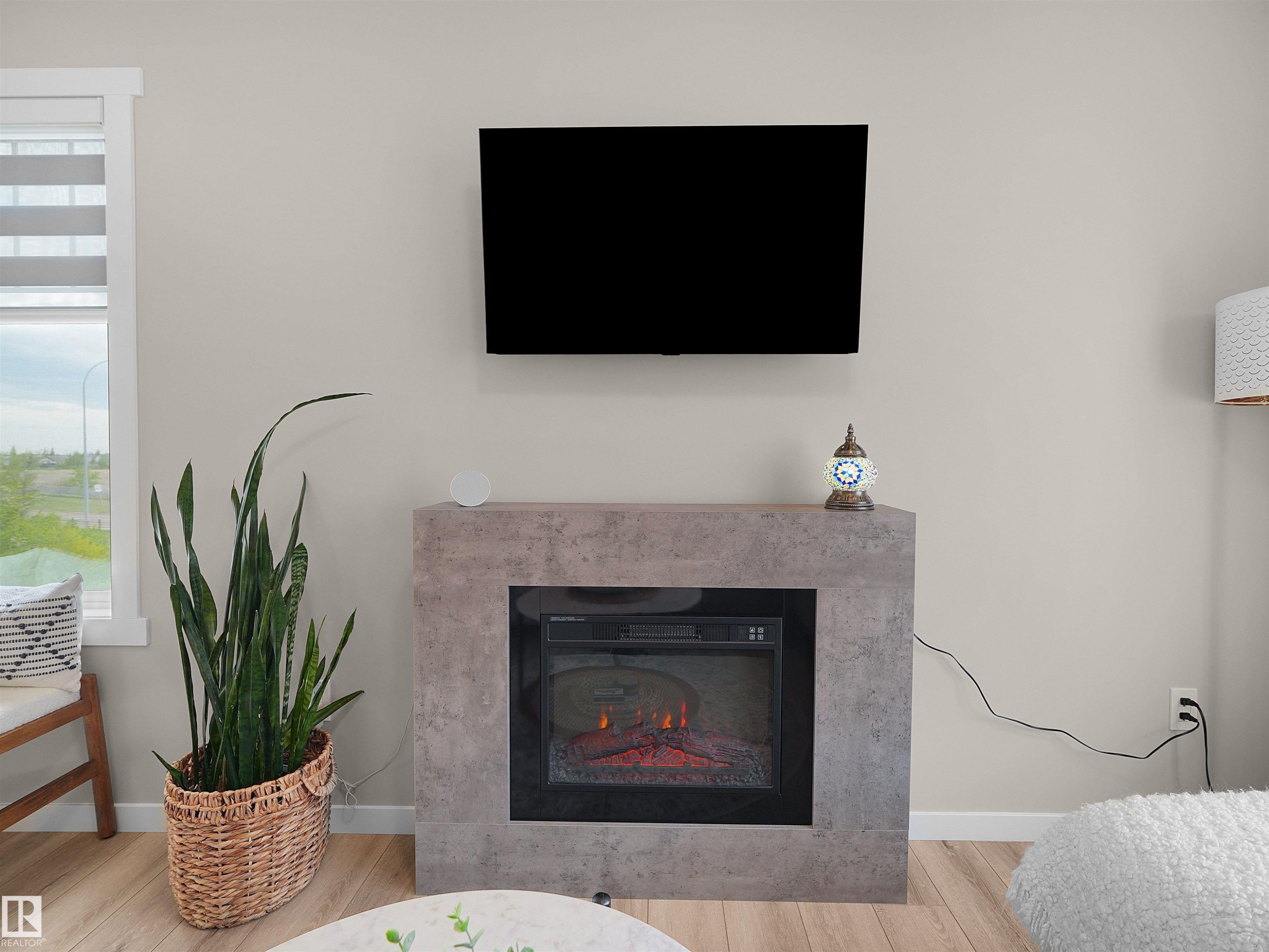 Modern electric fireplace with a concrete-look surround, featuring a display screen mounted above - #49 17832 78 St Nw, Edmonton, AB - Indoor Photo Showing Living Room With Fireplace