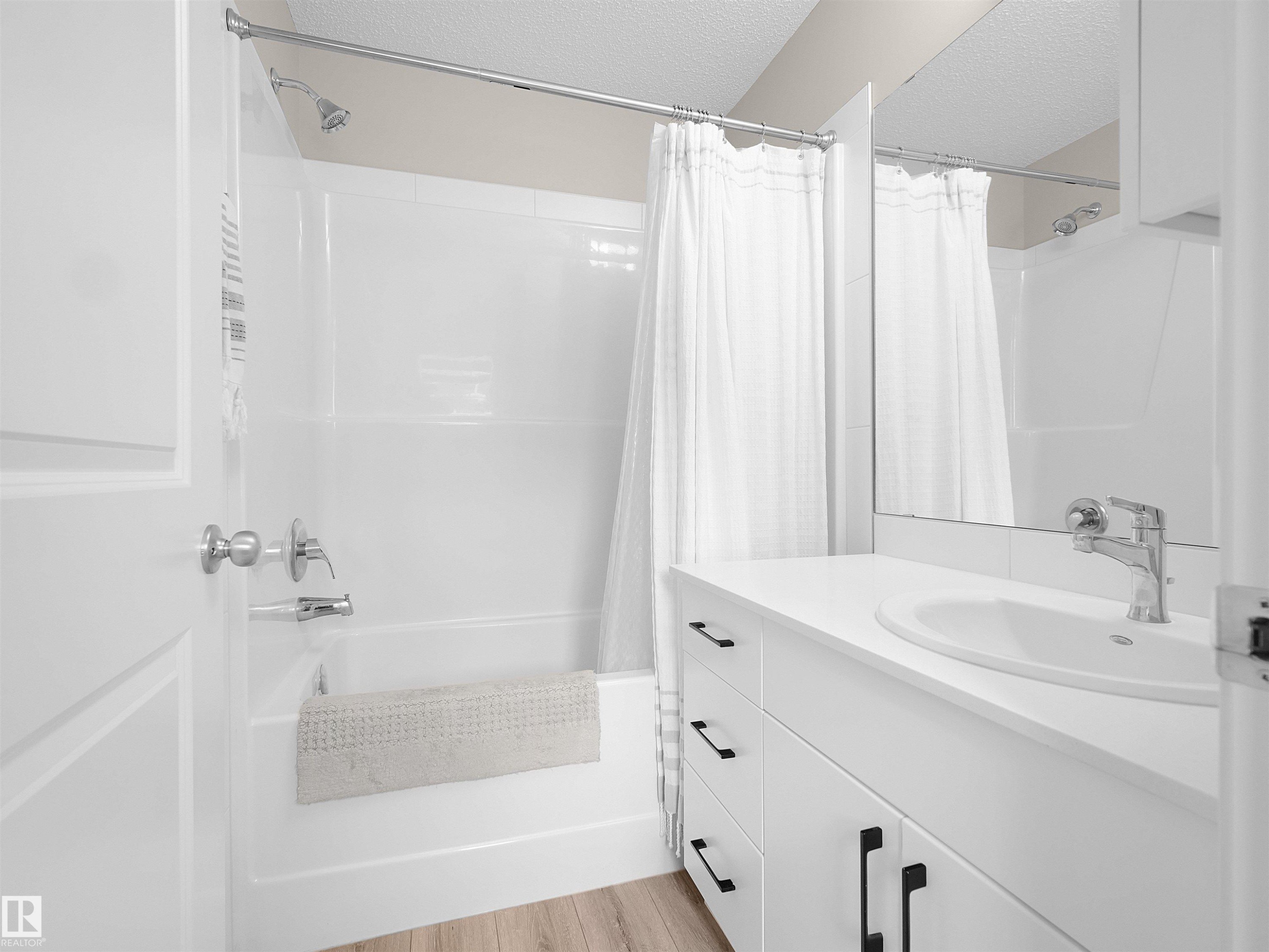 Bathroom featuring a white vanity with an undermount sink, a chrome faucet, and black hardware - #49 17832 78 St Nw, Edmonton, AB - Indoor Photo Showing Bathroom