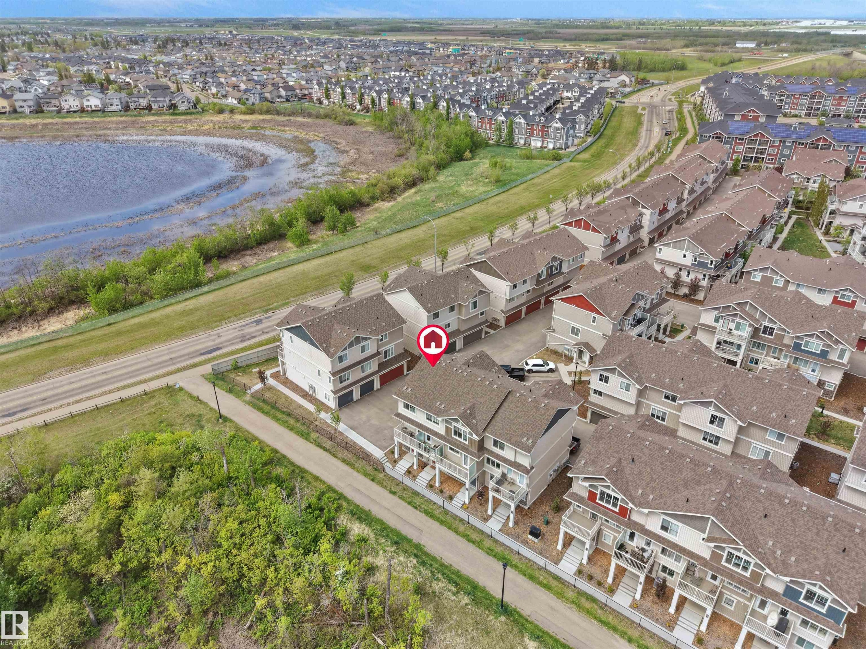 Townhouse property with a distinctive red garage door, featuring an upper-level balcony and a paved driveway - #49 17832 78 St Nw, Edmonton, AB - Outdoor With View