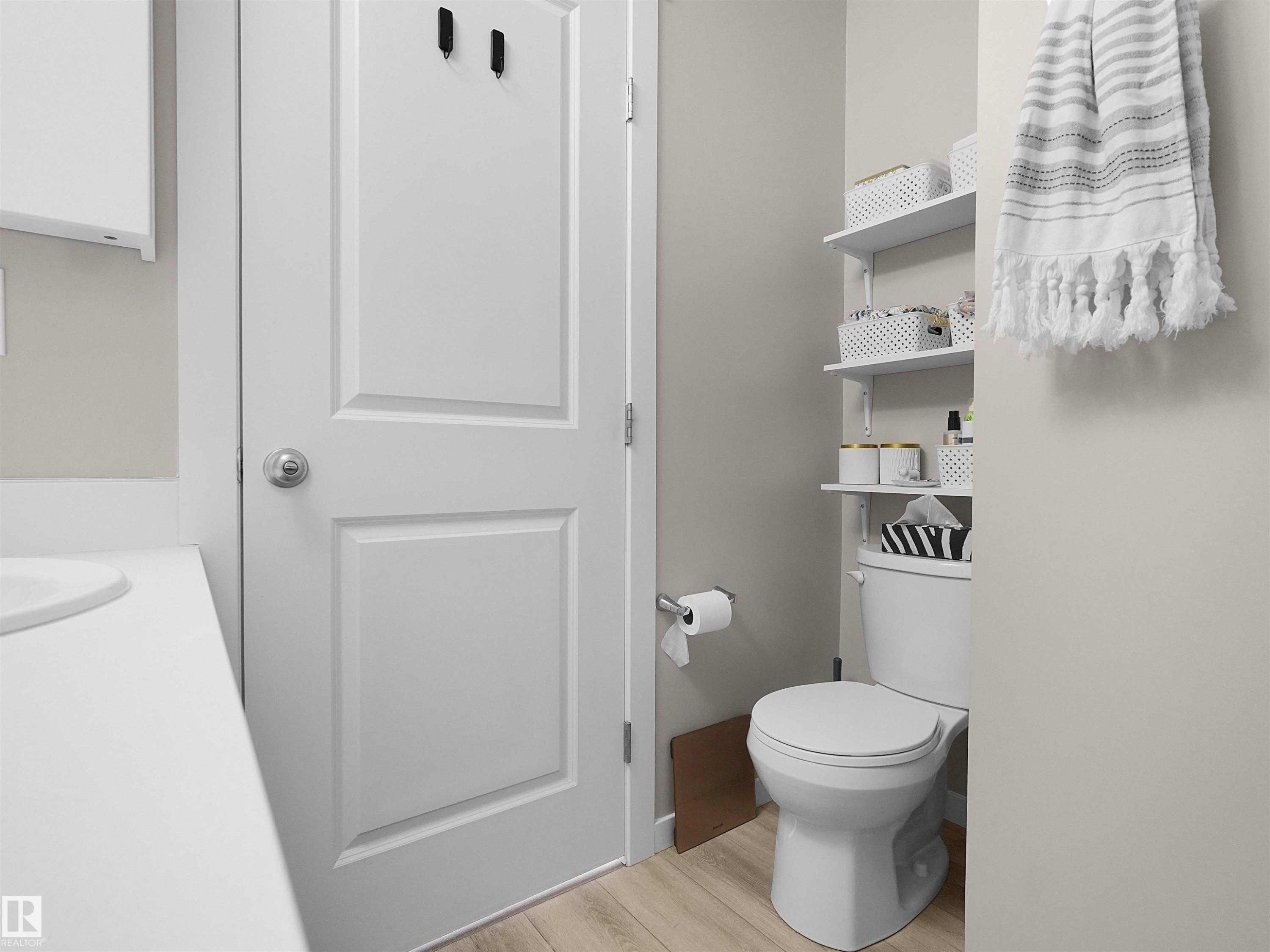 Bathroom featuring white panel door, white vanity countertop, and wood-finish flooring - #49 17832 78 St Nw, Edmonton, AB - Indoor Photo Showing Bathroom