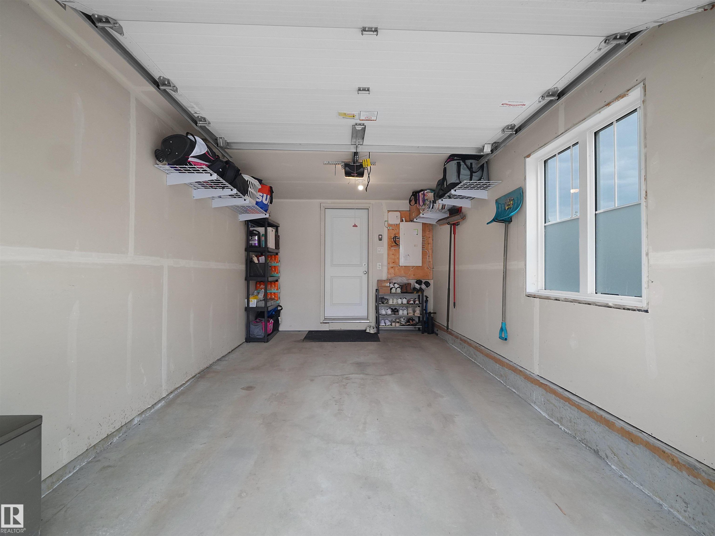 Spacious garage with concrete flooring, overhead storage racks, and a single window providing natural light - #49 17832 78 St Nw, Edmonton, AB - Indoor Photo Showing Garage