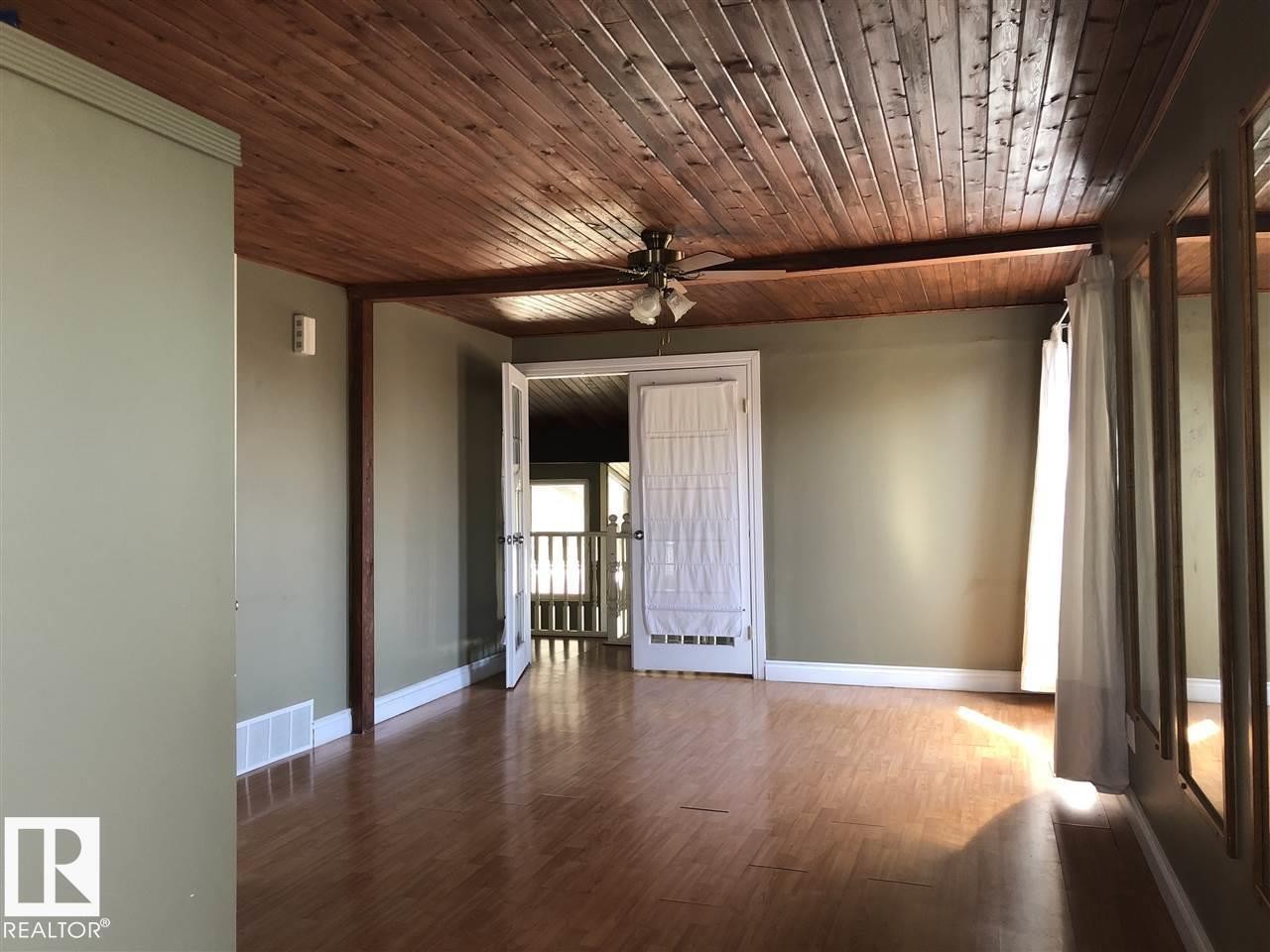 Room featuring wood-finish flooring, a plank wood ceiling, and a ceiling fan with integrated lighting - 11507 141 Avenue, Edmonton, AB