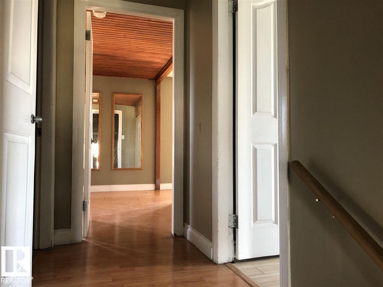 Interior hallway featuring wood-finish flooring, a wood-paneled ceiling, and neutral-toned walls - 11507 141 Avenue, Edmonton, AB