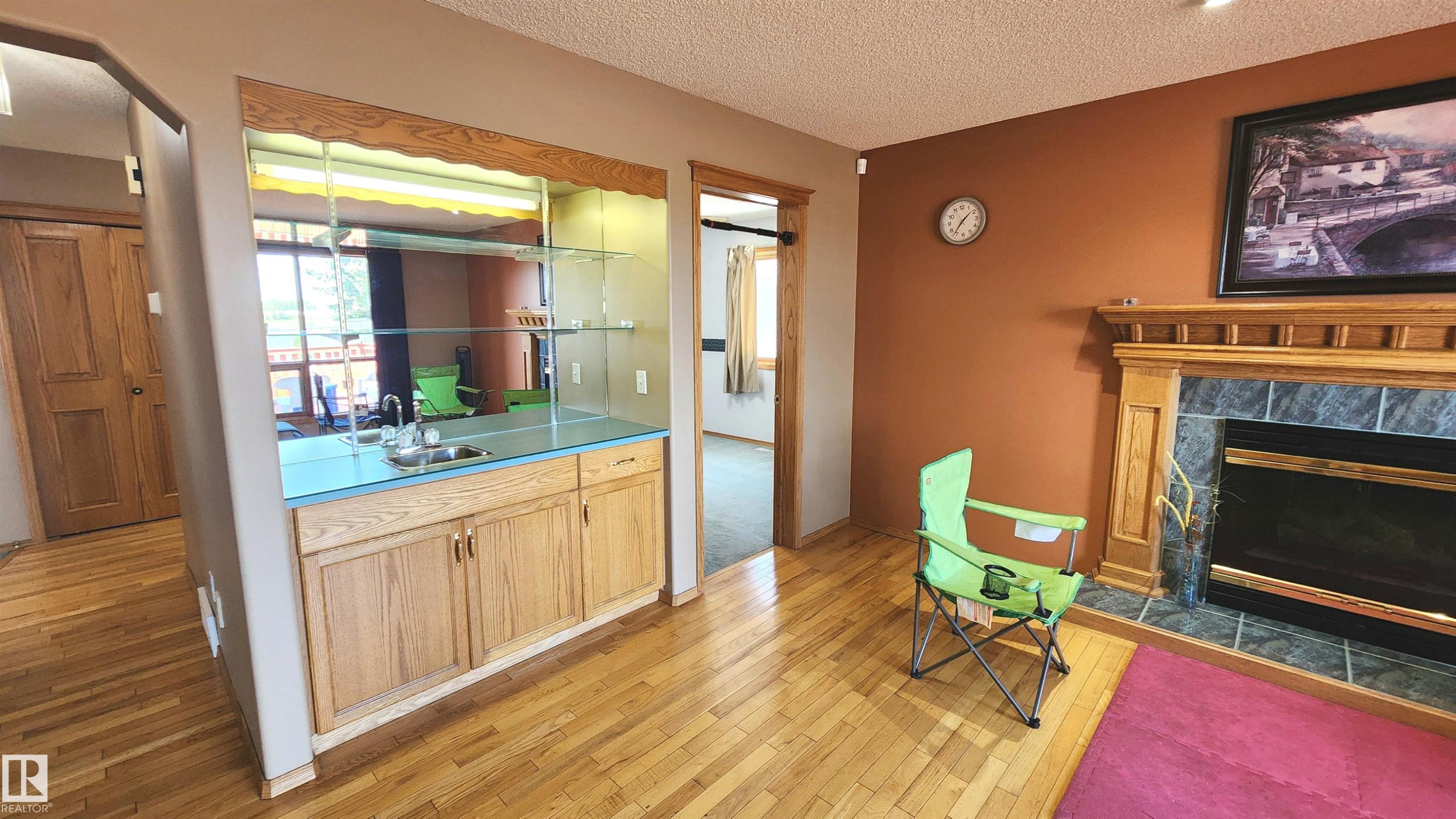 Hardwood flooring throughout featuring a built-in wet bar with mirrored backsplash and glass shelving - 2708 44A Avenue, Edmonton, AB
