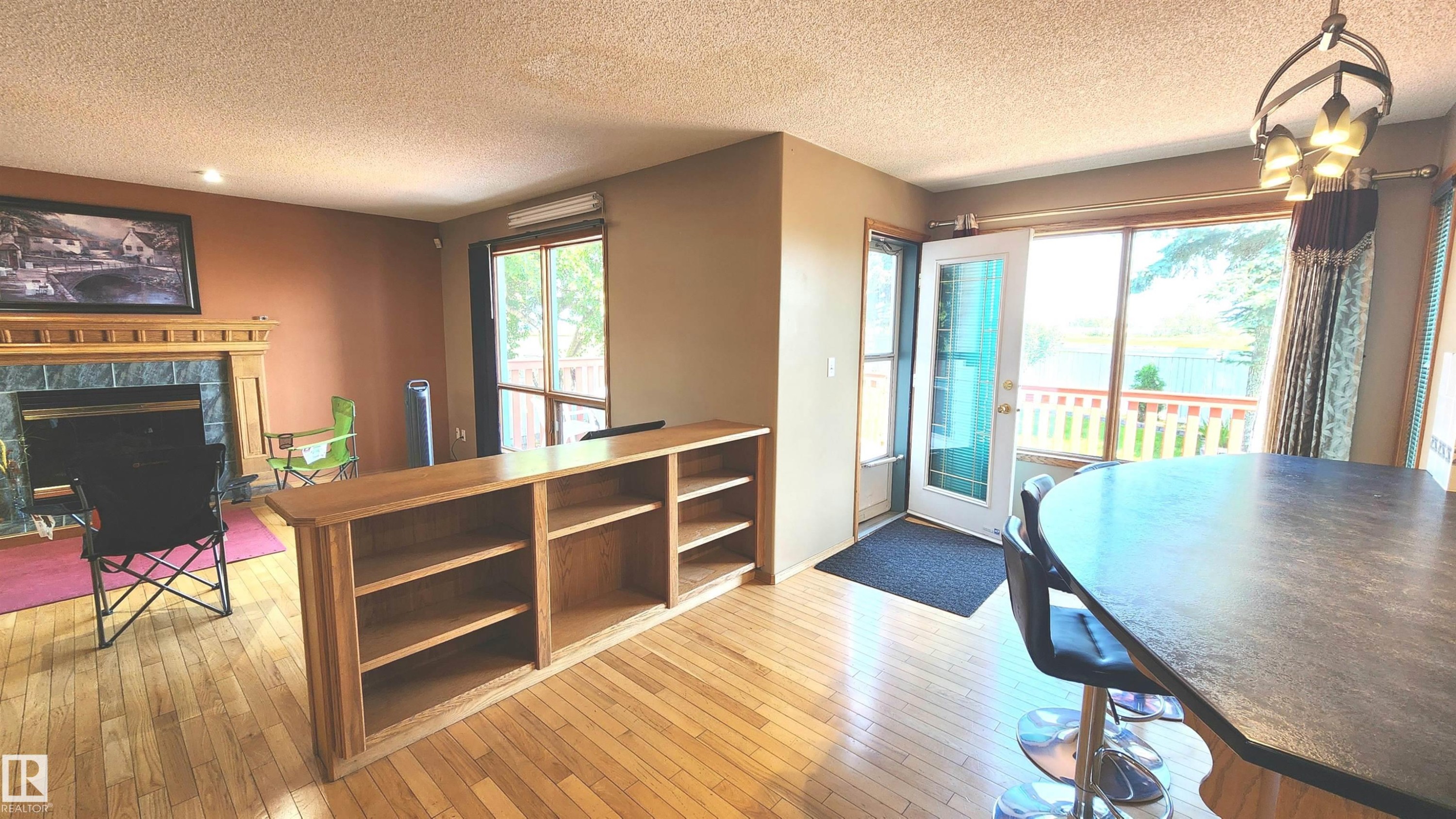 Open-concept living area featuring wood-finish flooring, a built-in bookshelf, and a fireplace with a stone surround and wood mantle - 2708 44A Avenue, Edmonton, AB