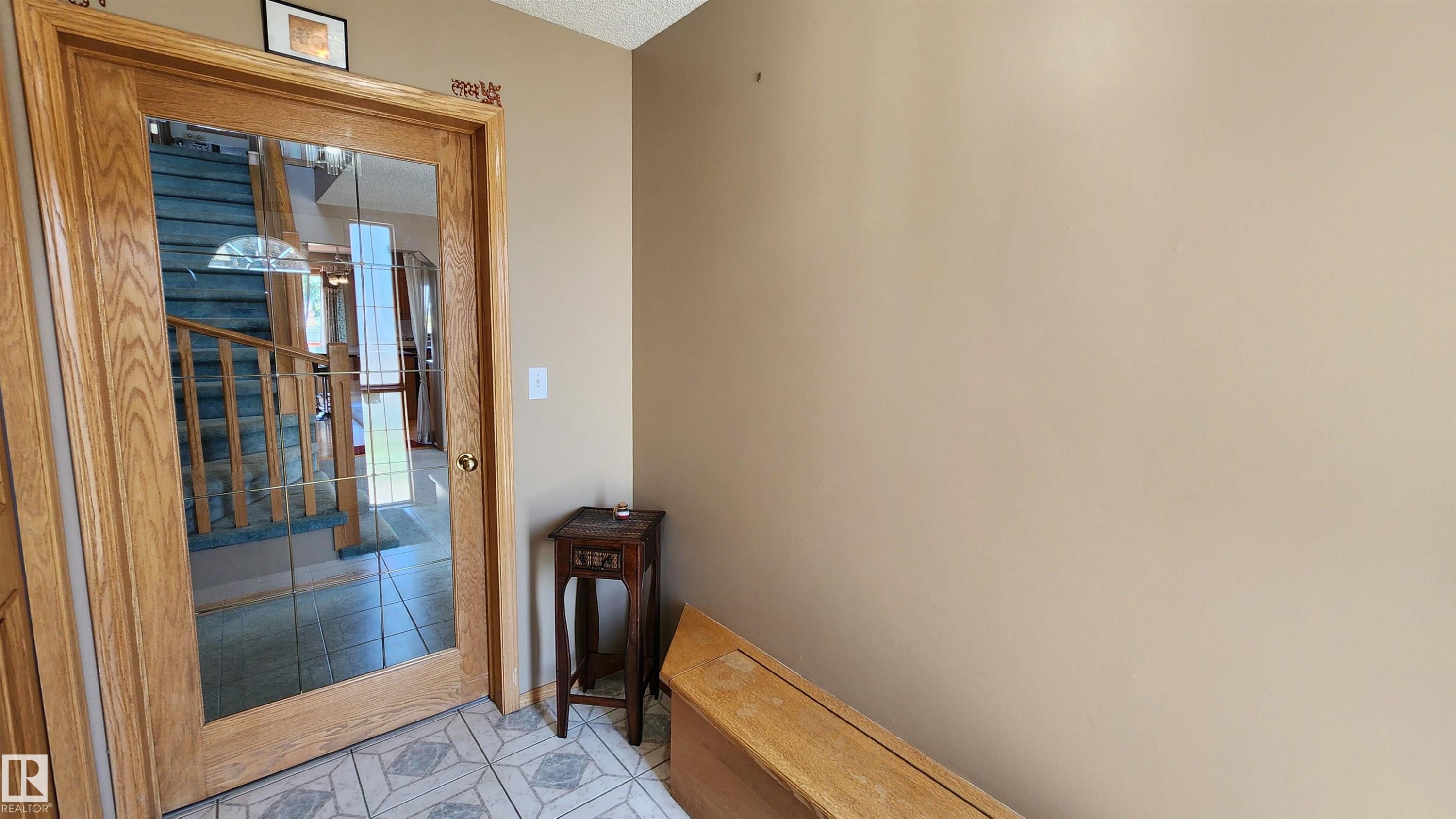 Entryway featuring a wood-framed door with glass panels, patterned tile flooring, and a neutral wall color - 2708 44A Avenue, Edmonton, AB