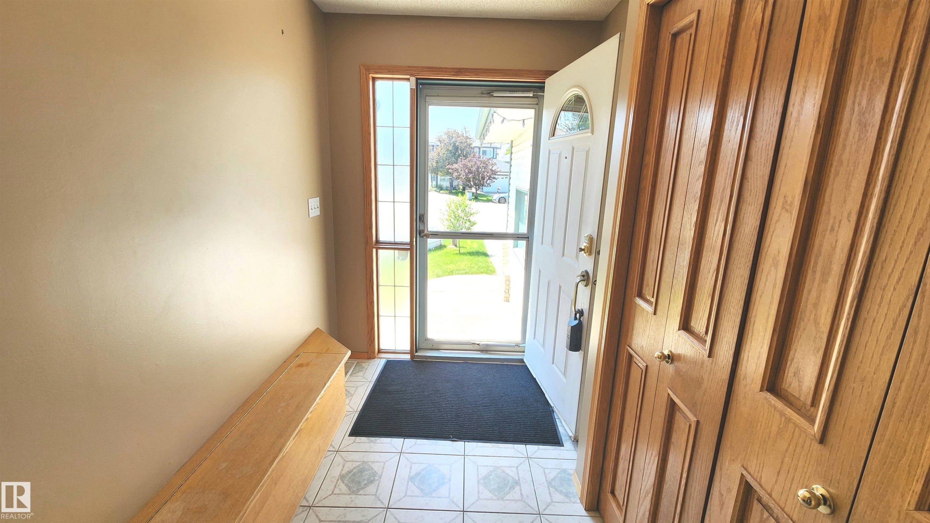 Foyer featuring tile flooring, a side light window, and a built-in wooden bench - 2708 44A Avenue, Edmonton, AB