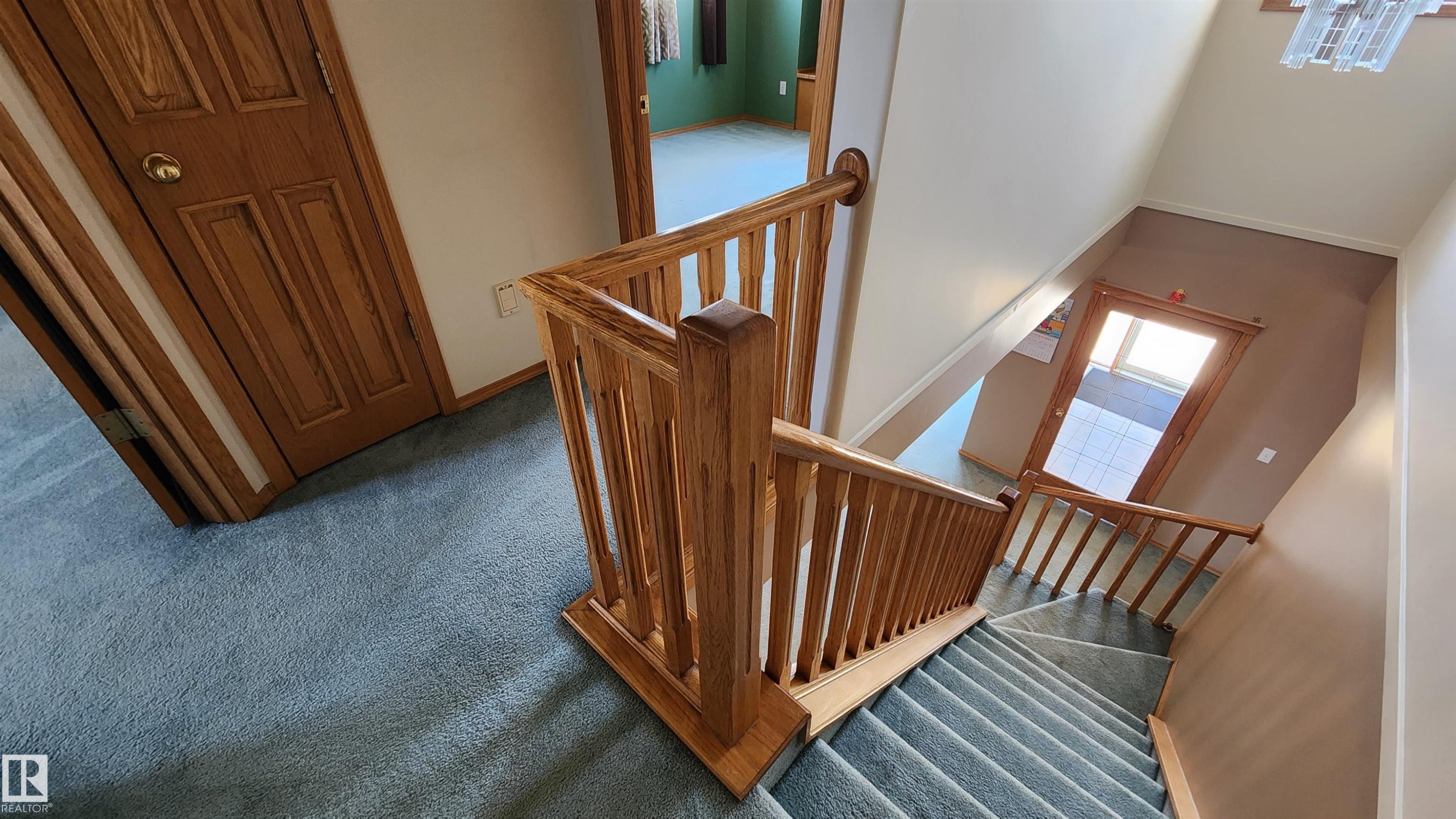 Staircase featuring wood railings and balusters, light blue carpet, and light beige walls - 2708 44A Avenue, Edmonton, AB