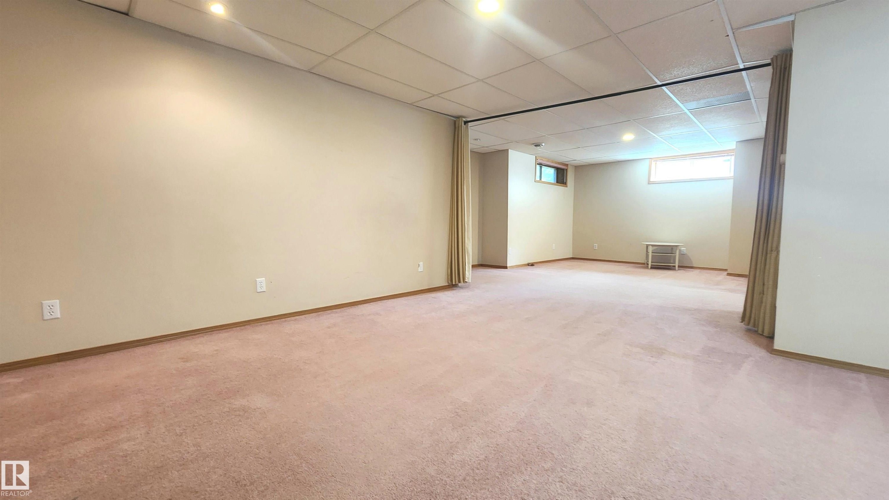 Spacious lower-level room featuring soft pile carpeting, light-toned wall paint, recessed lighting, and drop ceiling - 2708 44A Avenue, Edmonton, AB