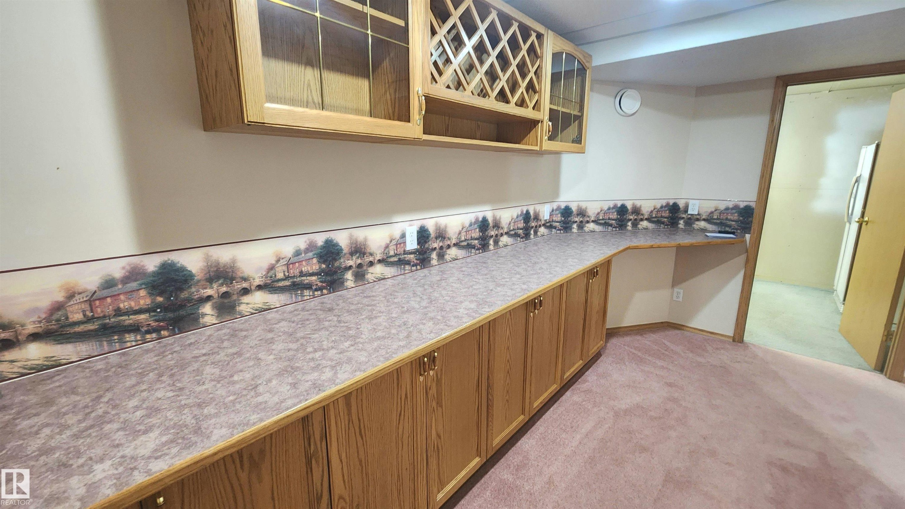 Extensive counter space with wood-finish base cabinetry and upper wall-mounted cabinets, including a built-in wine rack - 2708 44A Avenue, Edmonton, AB
