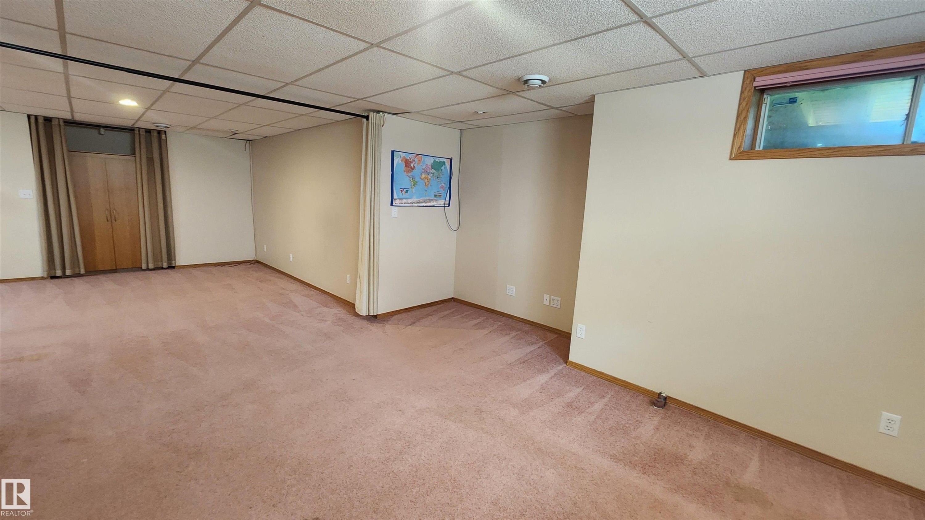 Spacious room with pink carpeting, a grid-panel ceiling, and neutral-toned walls - 2708 44A Avenue, Edmonton, AB