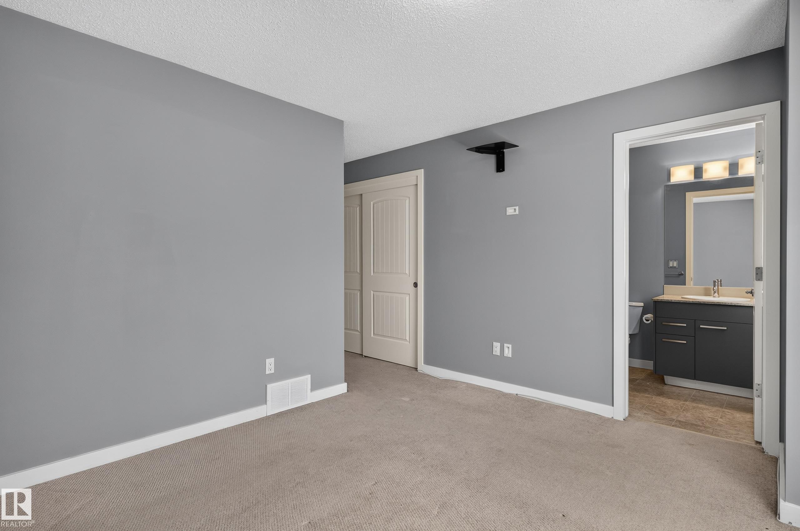 Spacious room with light gray walls, textured ceiling, and neutral-toned carpet - 24 655 Watt Boulevard, Edmonton, AB