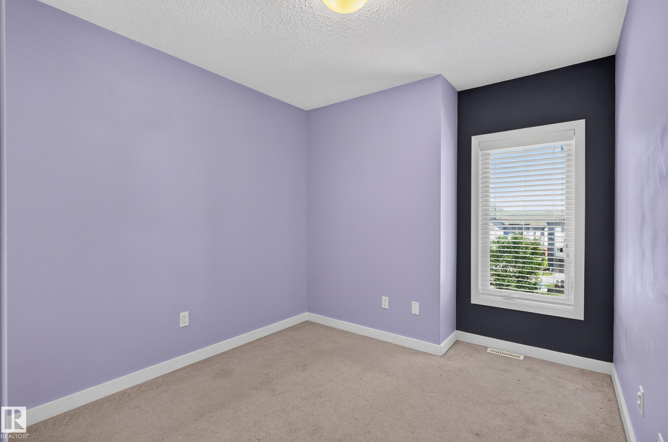 Carpeted room featuring a single window with blinds, white trim, and a textured ceiling - 24 655 Watt Boulevard, Edmonton, AB