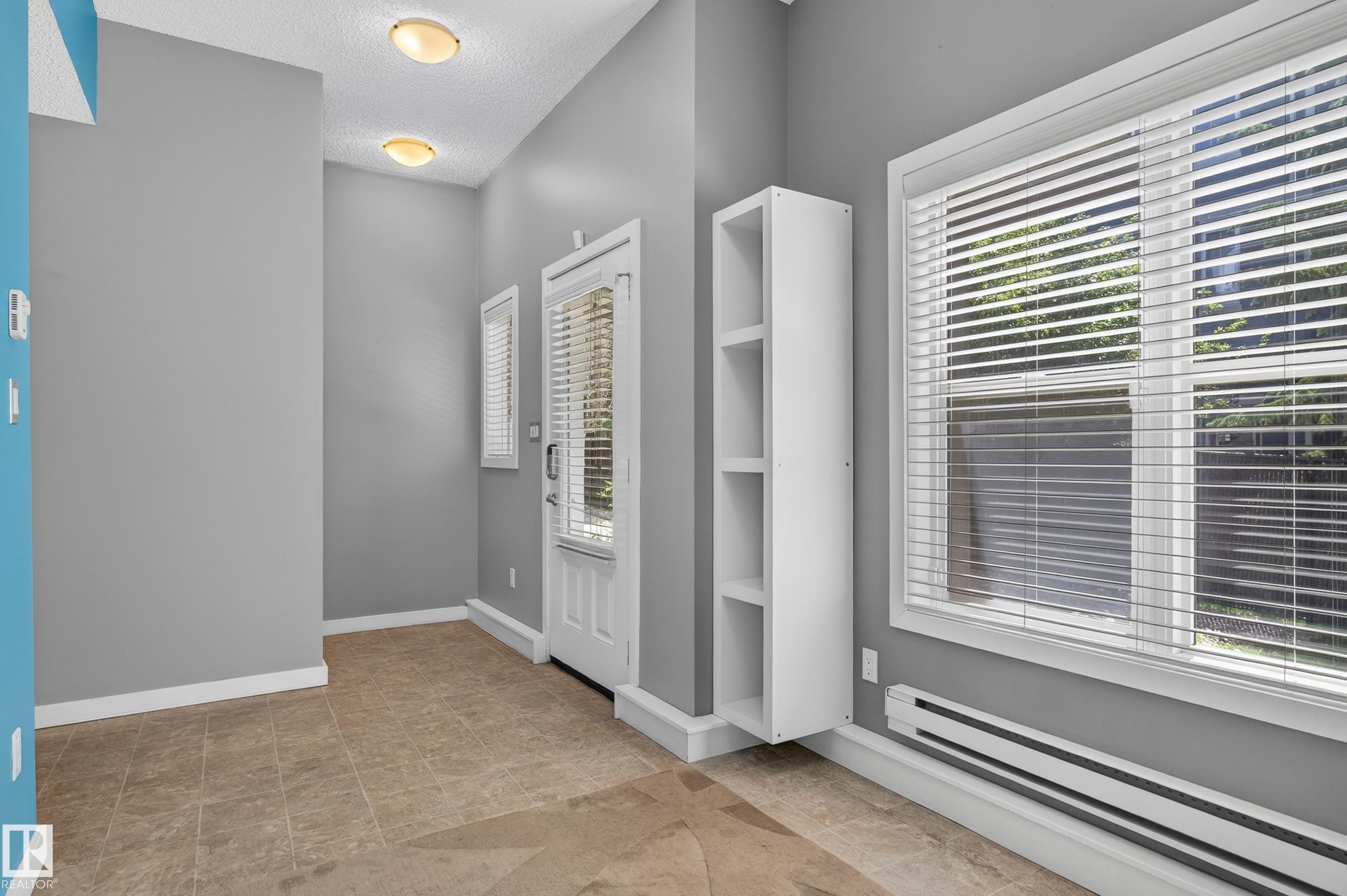 Entryway featuring tiled flooring, a white paneled door with glass inserts and window blinds, and recessed lighting - 24 655 Watt Boulevard, Edmonton, AB