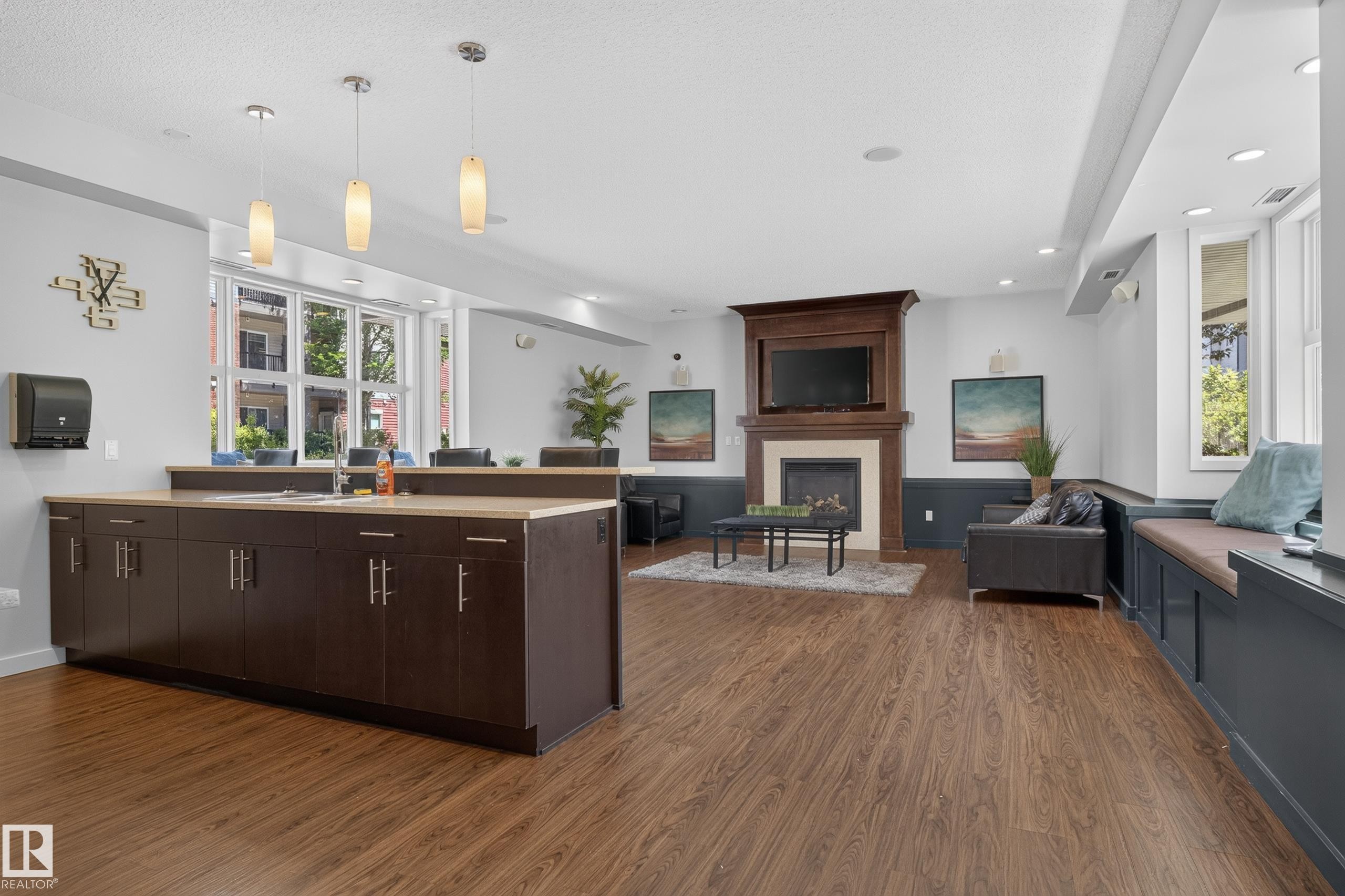 Open-concept room featuring wood-finish flooring and a central island with dark cabinetry and a light-toned countertop - 24 655 Watt Boulevard, Edmonton, AB