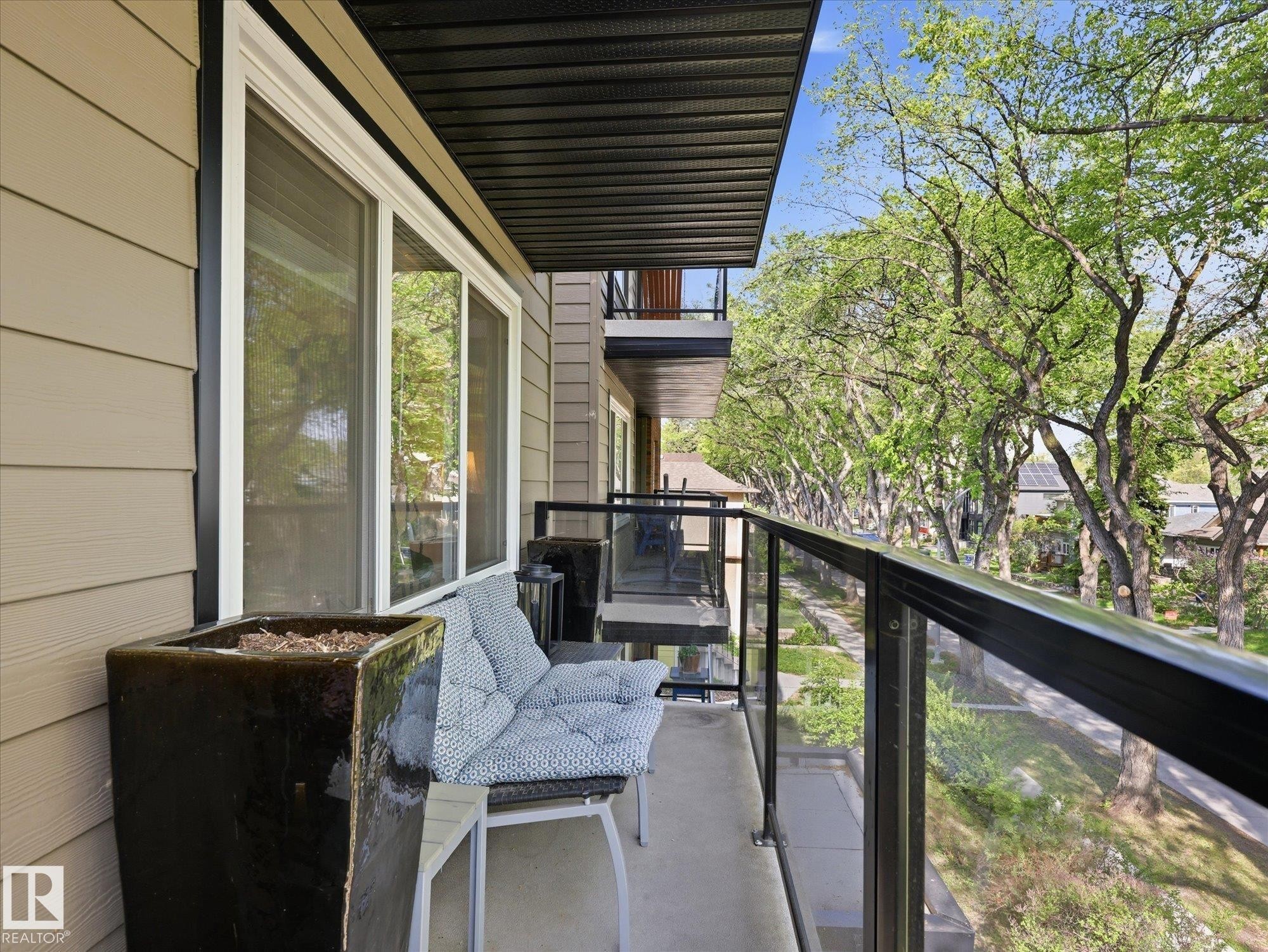 Balcony featuring glass panel railings, a concrete floor, and a black slatted ceiling - 301 10003 87 Avenue, Edmonton, AB - Outdoor With Exterior